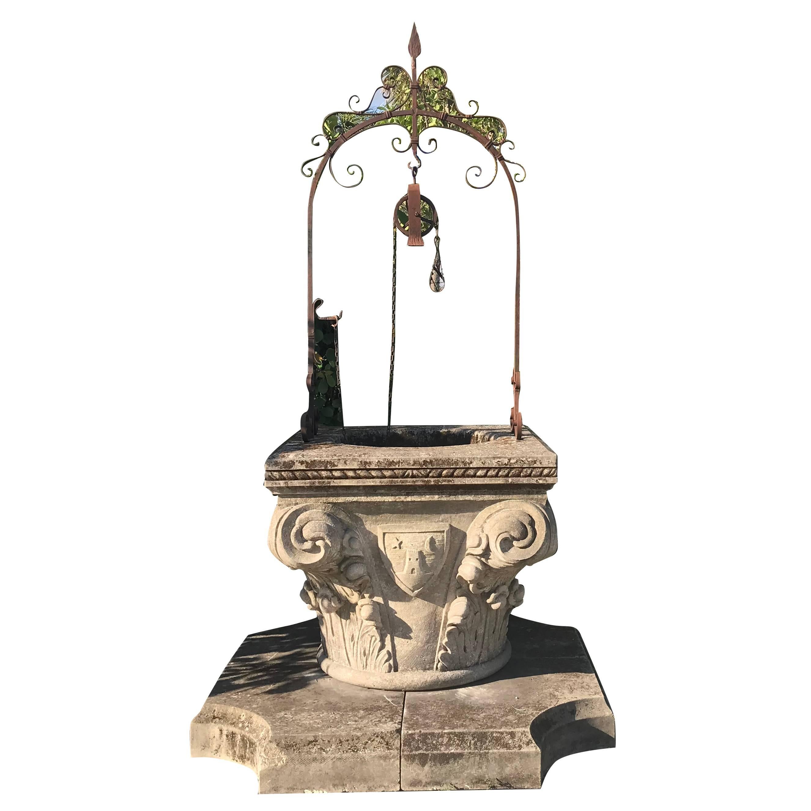 A large wellhead in the form of a Corinthian capital with heavy scrolls on each corner and positioned onto a limestone step, late Renaissance style, Italy, circa 20th century. Hand-carved details in Limestone with the original hand-forged iron