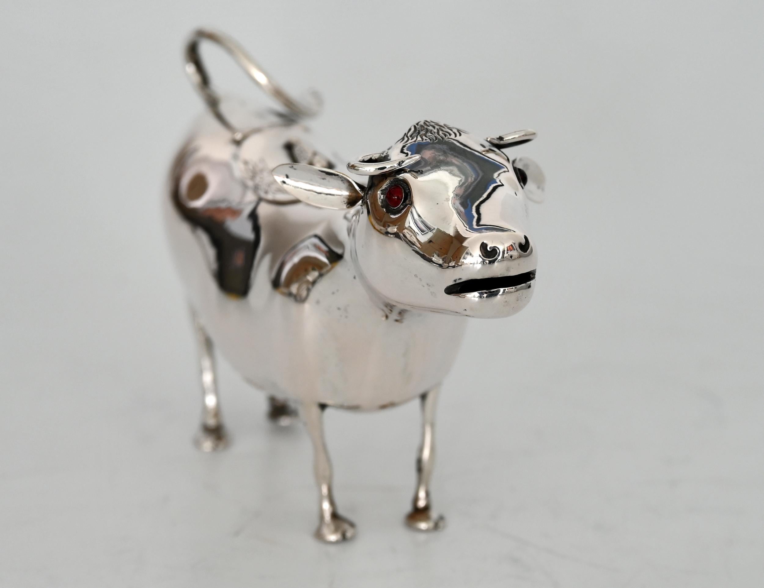 A cream pourer in the shape of a cow made of silver. By means of the lid on the back, the cow can be filled with milk or cream. The handle is easy to grip and can be used well to pour. The lid is provided with a bow tie. A particularly nice finish