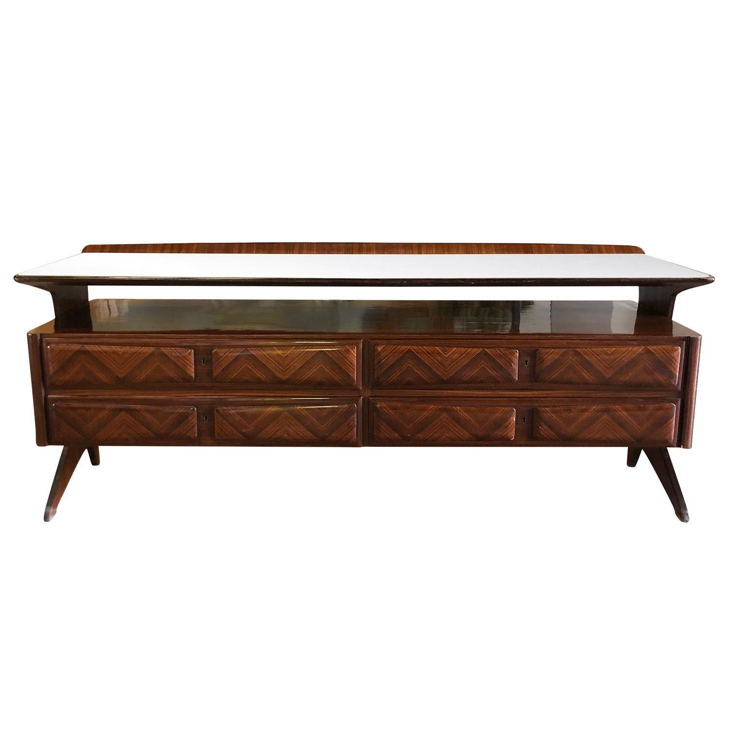A brown, vintage Mid-Century Modern Italian credenza made of hand crafted lacquered palisanderwood with four drawers and a glass top, designed by Vittorio Dassi in good condition. The storage piece is ideal as a traditional sideboard. Stunning