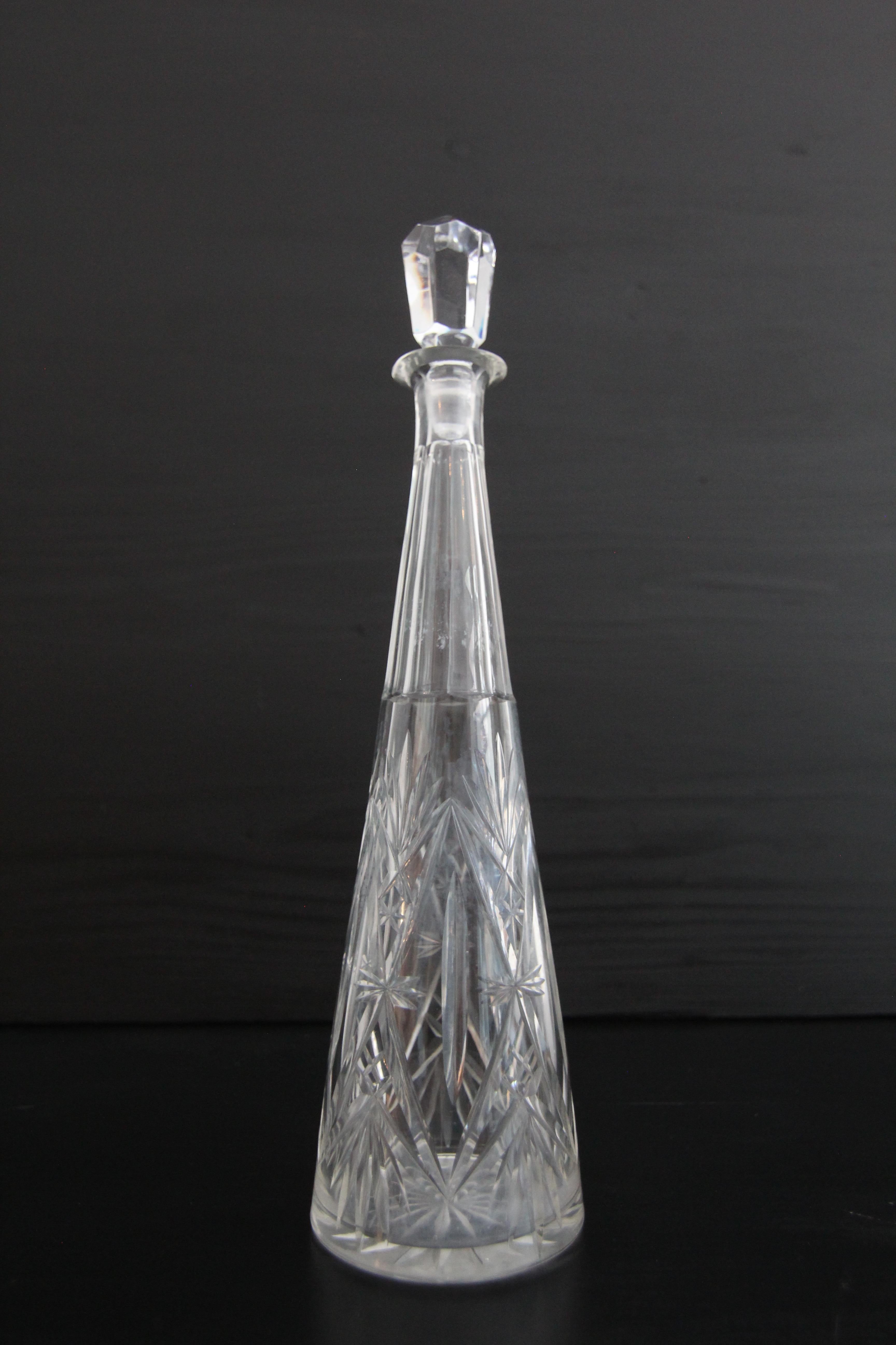 Une carafe en verre de cristal conique avec une coupe en biseau. Probablement des années 1960. 

L'artisanat traditionnel du soufflage et de la découpe du verre transforme le cristal en un objet sophistiqué caractérisé par sa clarté et sa brillance.