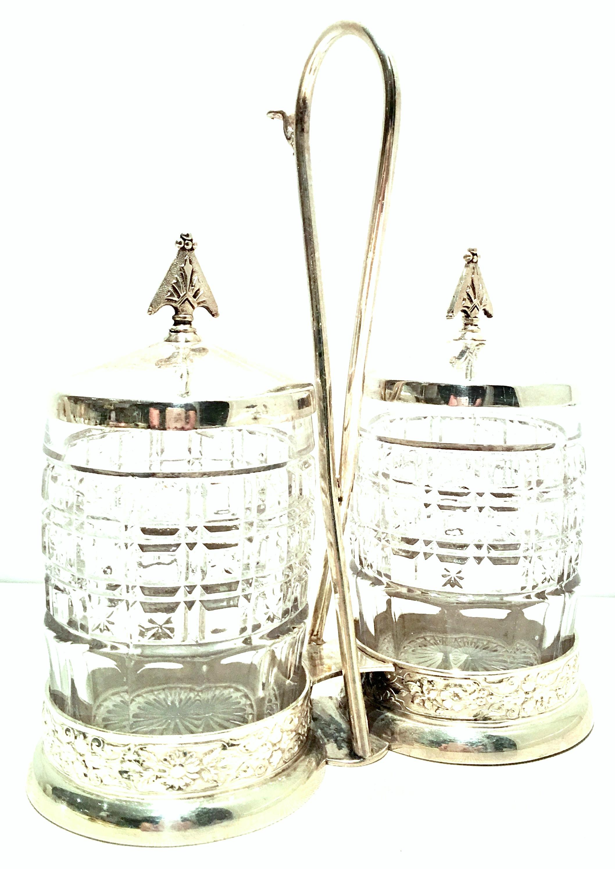 20th century cut crystal & silver plate cruet set of three pieces. This lovely cut to clear crystal and silver plate three-piece cruet set includes, two cut crystal cruet or condiment jars with silver plate lids and one silver plate caddy.
Each jar