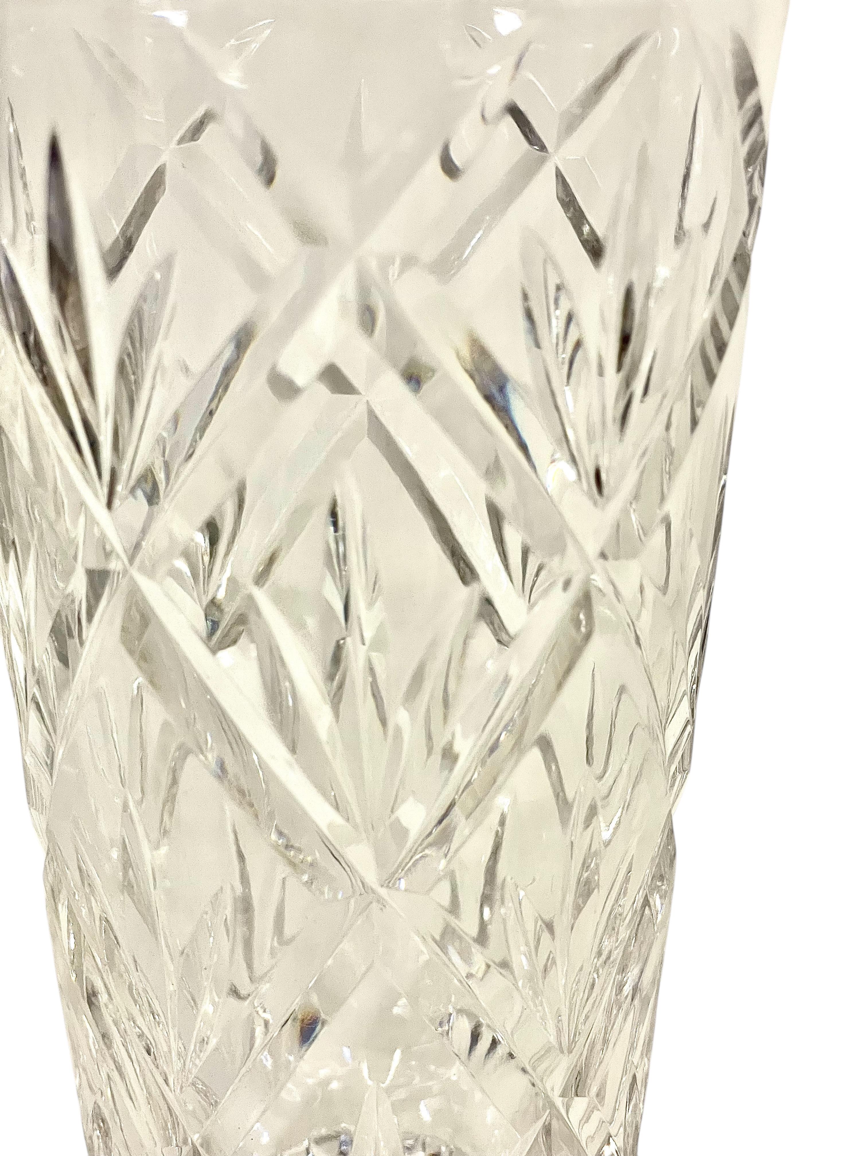 Ce vase en cristal taillé du 20e siècle présente un étonnant motif géométrique avec des hachures et des étoiles complexes, reflétant magnifiquement la lumière sous tous les angles. La forme conique classique met en valeur son design raffiné, ce qui