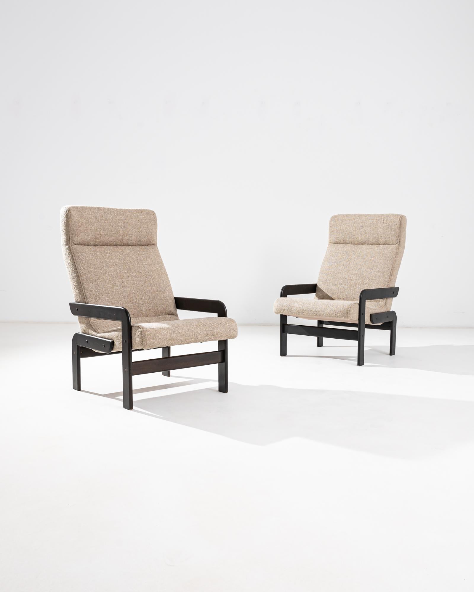 A unique silhouette in stylish black and beige gives this pair of vintage armchairs a Modernist appeal. Made in Czechia in the 20th century, the intriguing geometric shapes of the wooden frame engage the eye. The seat is angled at a relaxing