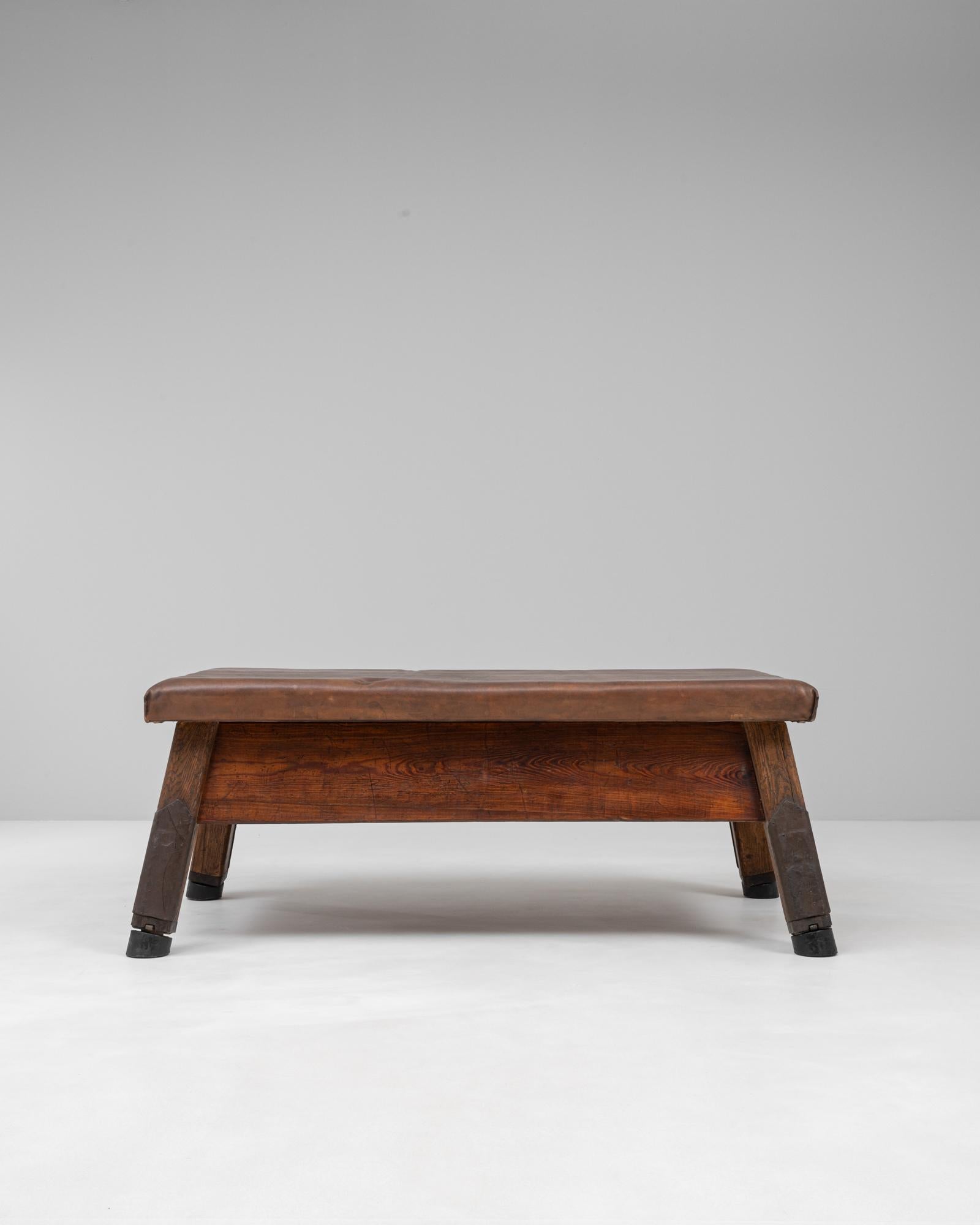 Ce banc de gymnastique tchèque du XXe siècle allie utilité industrielle et charme robuste. Utilisé à l'origine dans le cadre de l'entraînement sportif, il est doté d'un épais plateau en cuir cousu à la main, d'un riche ton brun qui s'est patiné au