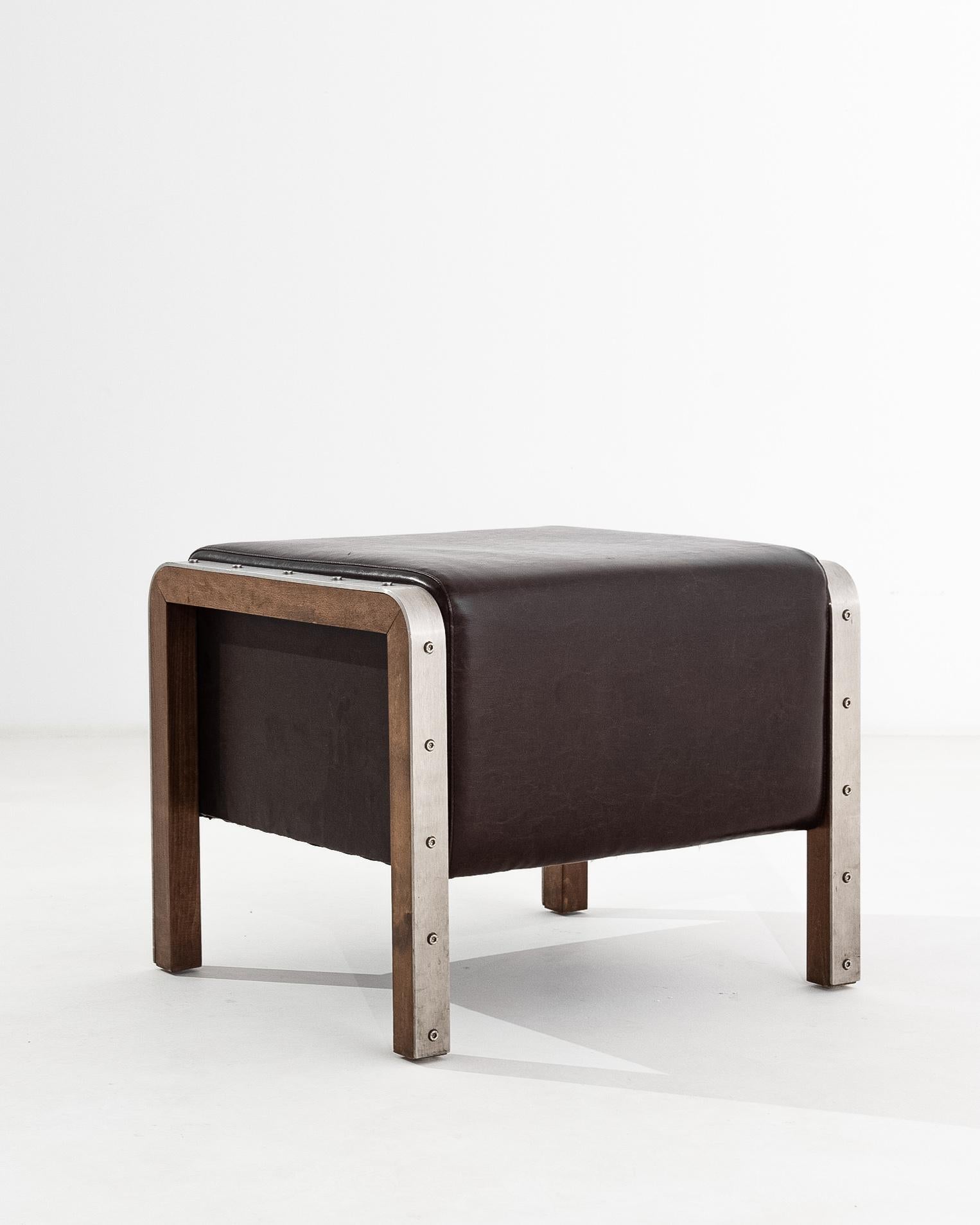 Chic and futuristic, this vintage leather ottoman offers a stylish piece of contemporary design. Made in Czechia in the 20th century, a deep cube upholstered in fine black leather offers an ample seat. A curved band of brushed steel is fixed onto