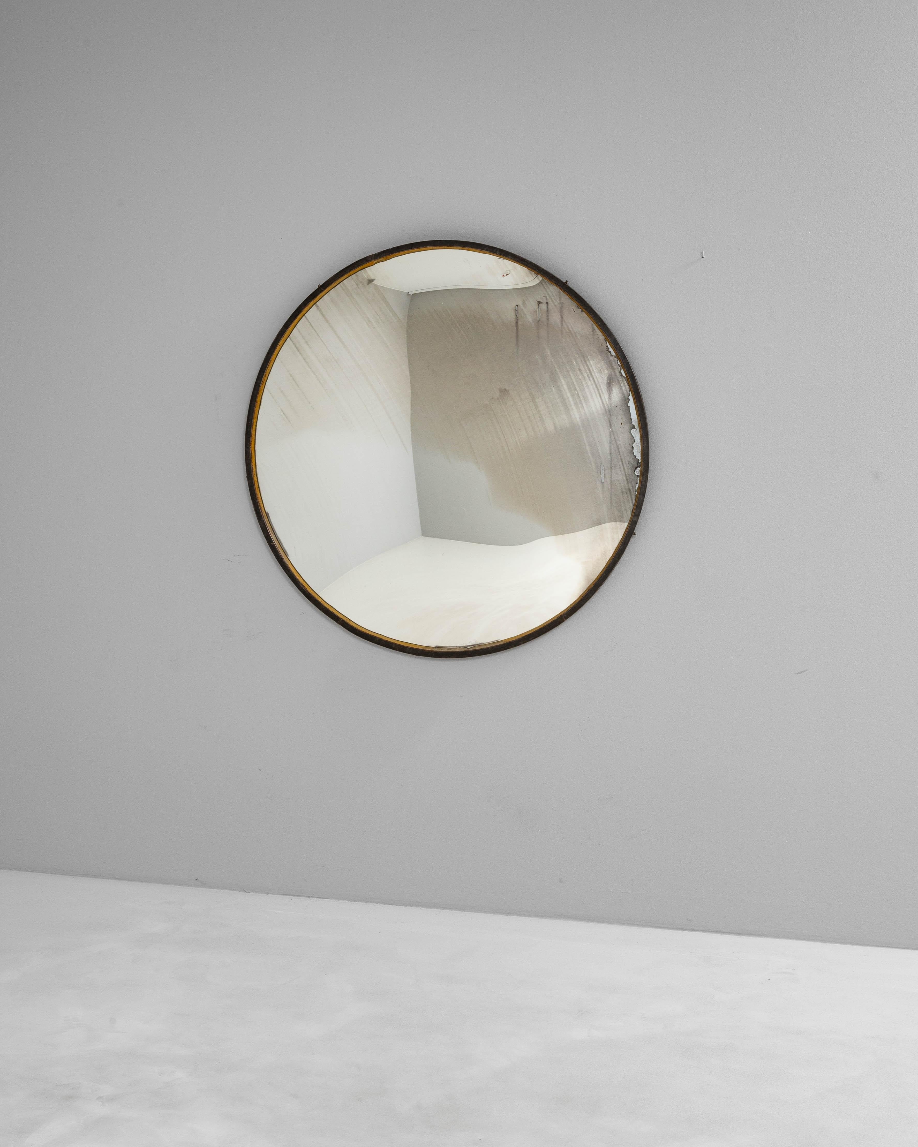 Miroir rond en métal tchèque du 20ème siècle présentant un design industriel minimaliste avec une patine subtilement vieillie. Le cadre en métal, fini dans un ton sombre avec des touches de laiton, ajoute un contraste raffiné au verre doucement