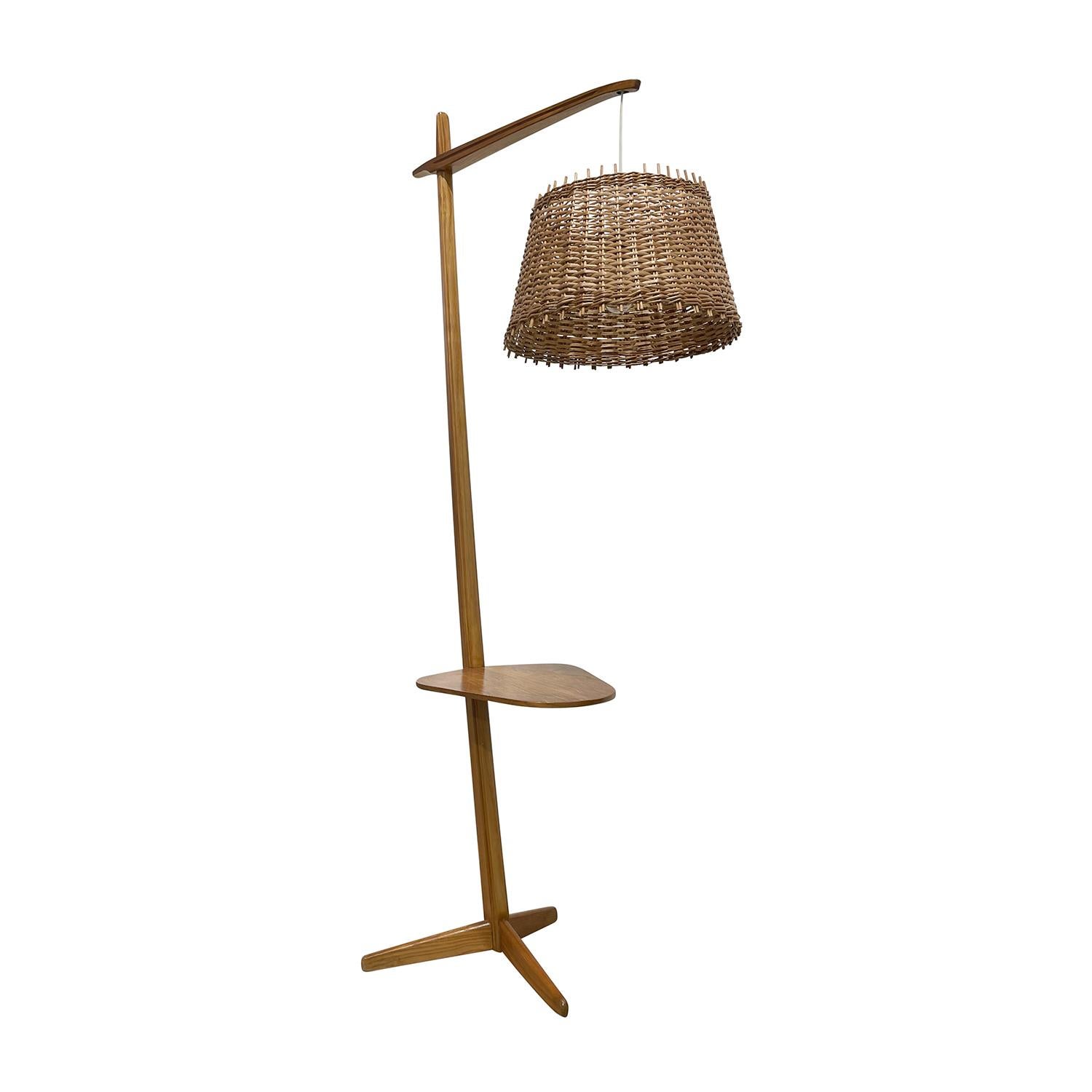 A light-brown, vintage Mid-Century Modern Czech reading floor lamp with an arched shelf, made of handcrafted Oakwood, designed and produced by Krasna Jizba in good condition. The detailed light is composed with its original round bamboo shade,