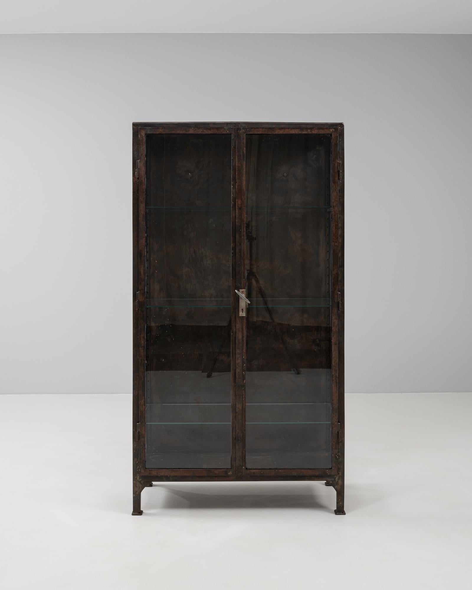 This 20th Century Czech medical cabinet combines utilitarian design with industrial sophistication. Crafted from polished steel, the frame has a rich, darkened patina that contrasts beautifully with the clear glass panels and interior shelving.