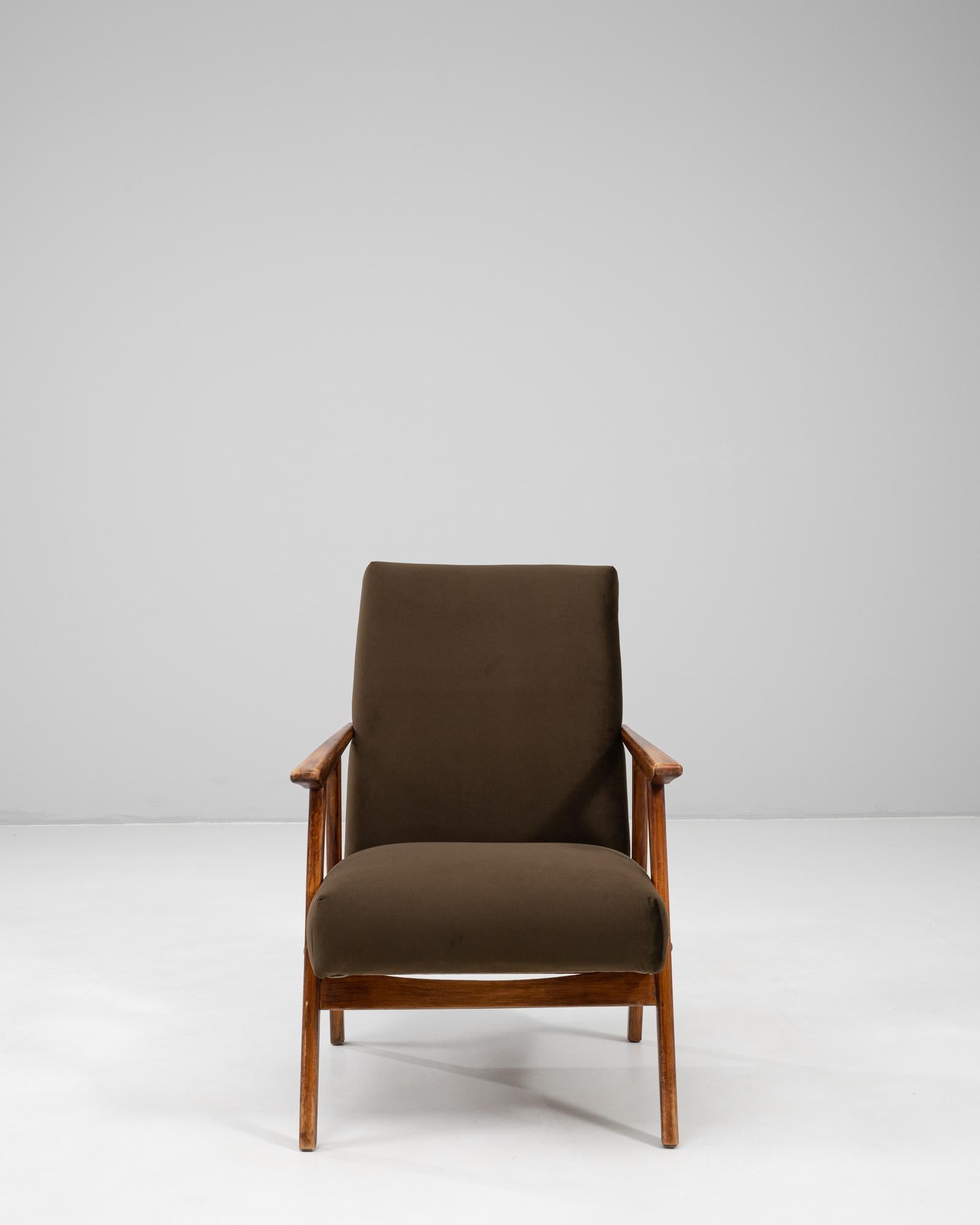 This 20th-century Czech upholstered armchair reflects the clean lines and functional elegance of mid-century design. Crafted with a solid wooden frame, the chair features gently tapered legs and angular armrests that emphasize its modern silhouette.