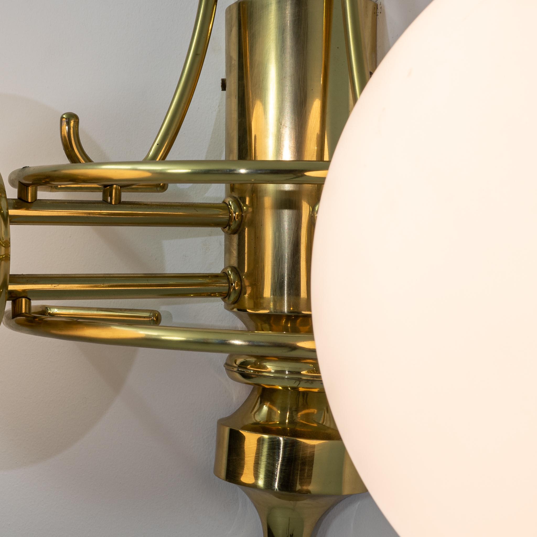Illuminate your space with the timeless charm of these 20th-century Czechia brass wall sconces. Crafted in the iconic Art Deco style, these sconces feature a stunning combination of brass and white opaque glass globes. The brass adds a touch of