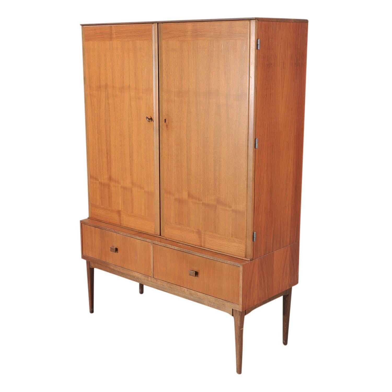 A 20th Century, vintage Mid-Century modern Danish dining room cabinet made of hand crafted polished, partly veneered Walnut, in good condition. The Scandinavian cupboard is composed with two large doors and two lower drawers which detailed by brass