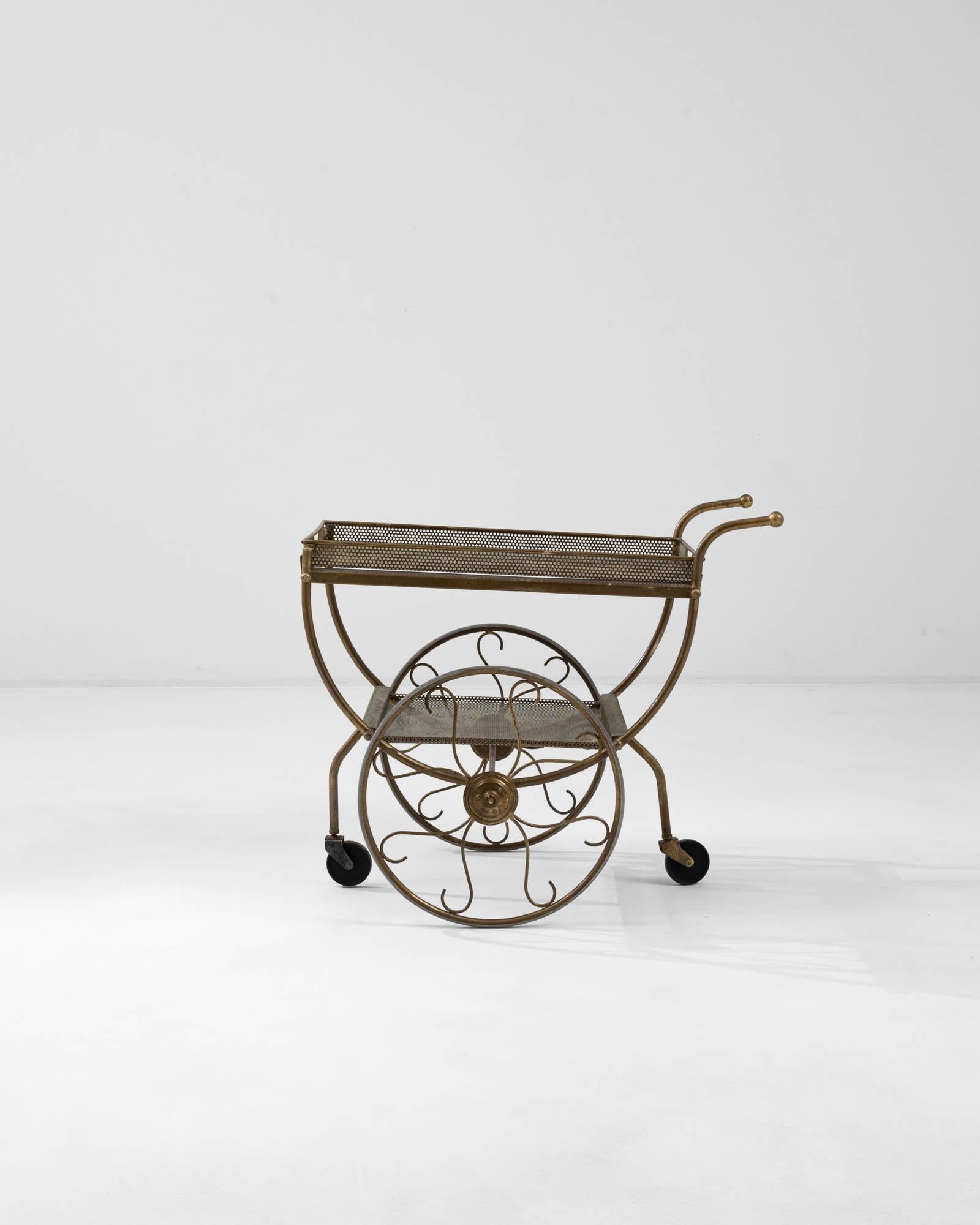 Indulge in the luxury of Danish design with the 20th Century Brass Bar Cart, a resplendent creation by the renowned Josef Frank. This piece exudes sophistication, with its radiant brass frame that glimmers under the light, capturing the essence of
