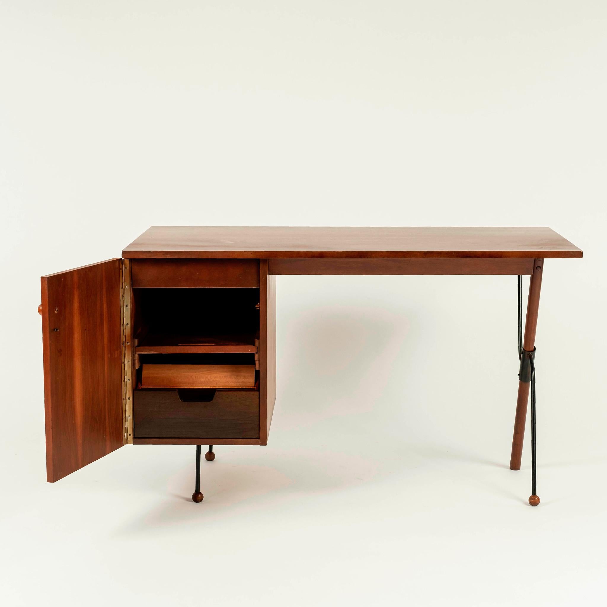 Modernist maple and patinated steel desk featuring two drawers behind a single hinged door with ball final feet and knob.