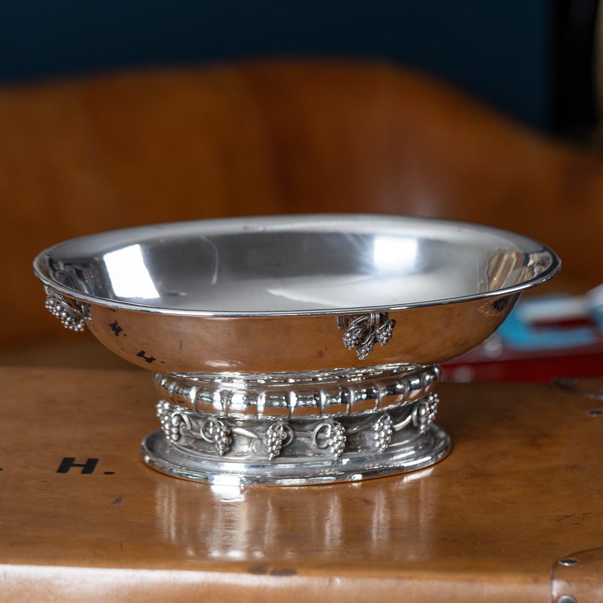 Bol de centre de table danois en argent massif Georg Jensen du milieu du 20e siècle à motif de vigne. Martelé à la main, ce grand bol ovale repose sur une base ovale entourée de grappes de raisin. Quatre anneaux de raisin articulés en forme de