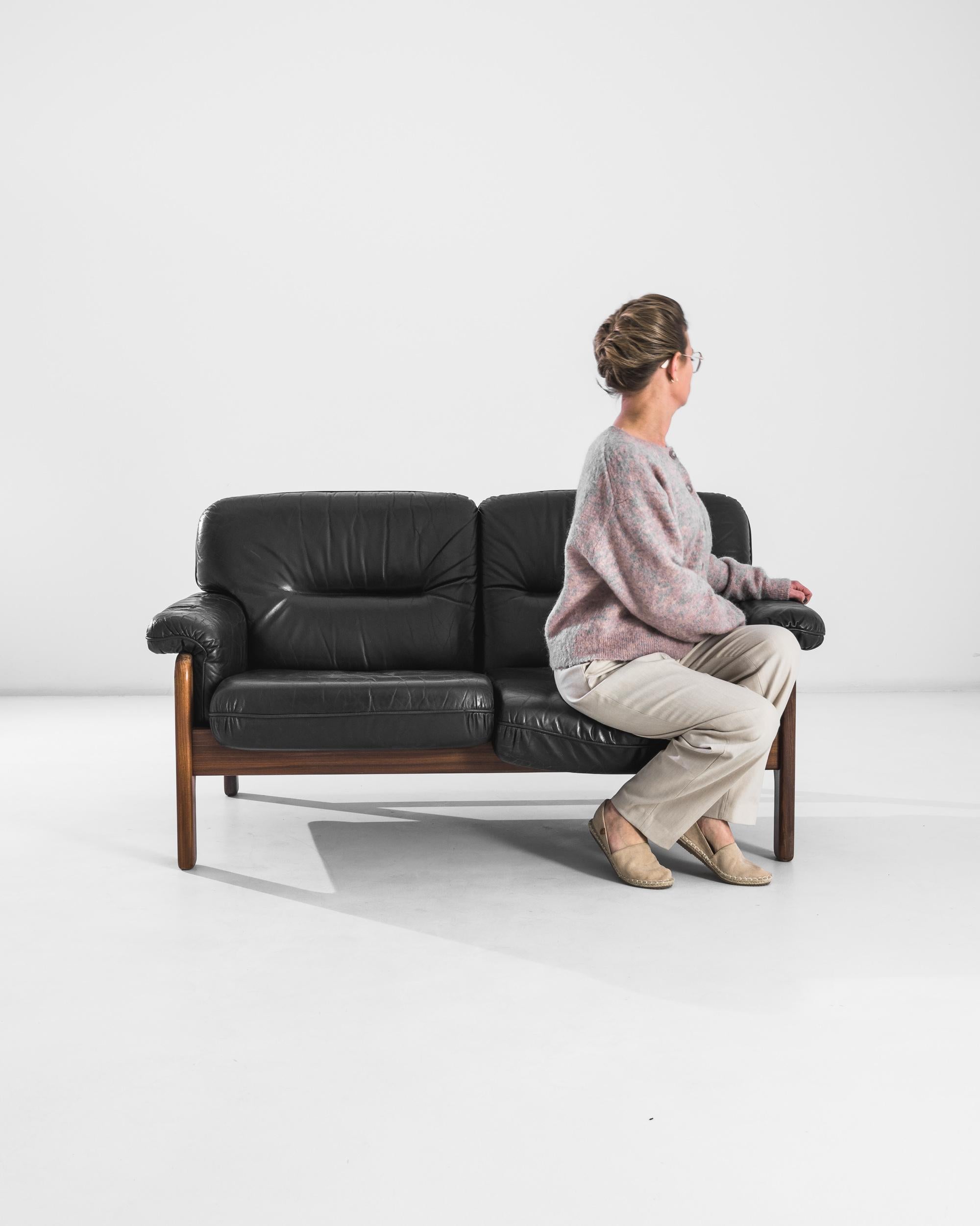 Dieses Ledersofa setzt sowohl in einem modernen Büro als auch in einem eleganten Wohnzimmer einen raffinierten Akzent. Die tiefschwarzen Lederkissen des im 20. Jahrhundert in Dänemark hergestellten Stuhls bieten eine luxuriöse Sitzfläche, die durch
