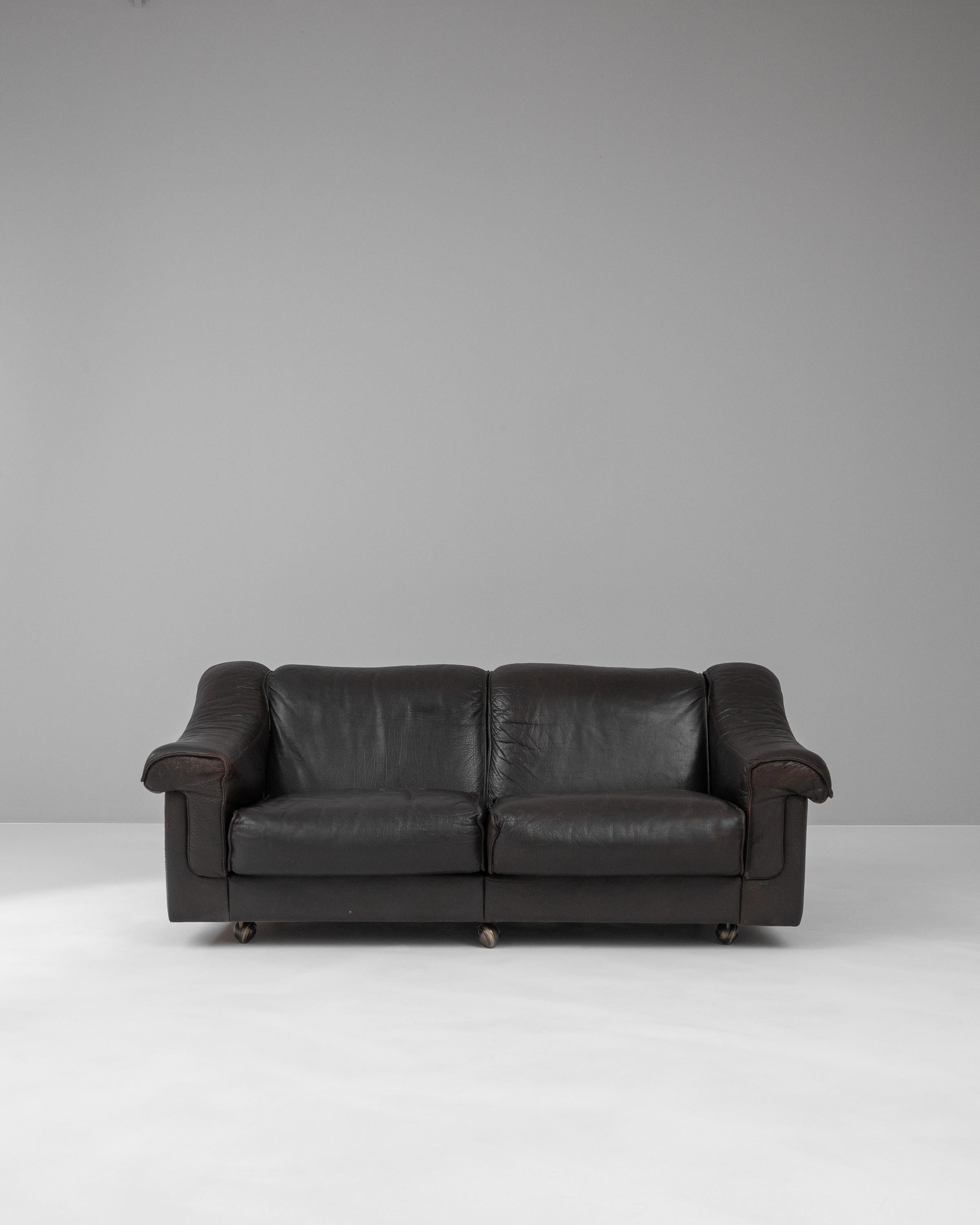 This 20th Century Danish Leather Sofa encapsulates the elegance of Scandinavian design, offering a seamless blend of style and comfort. Crafted with the utmost attention to quality, the sofa features rich, chocolate leather that has matured with