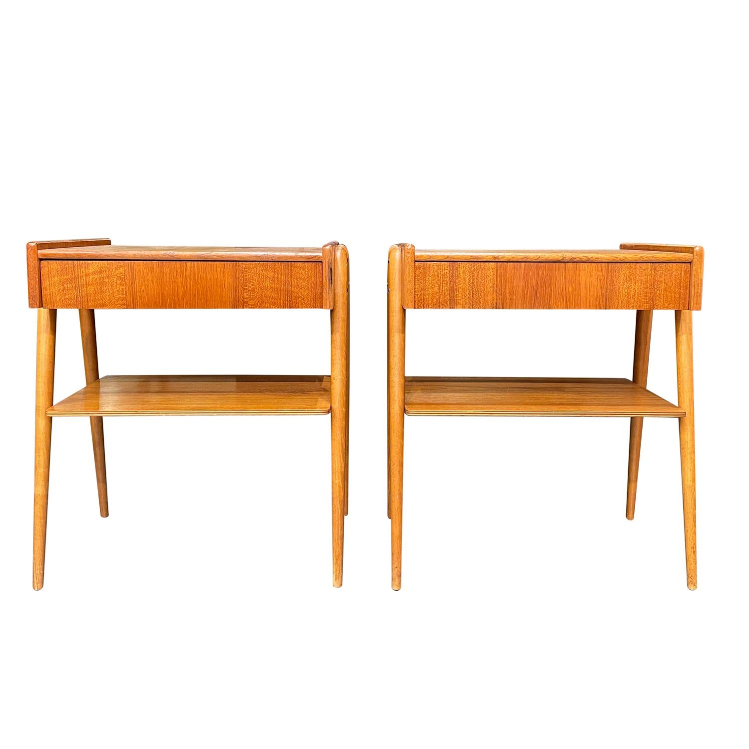 A vintage Mid-Century modern Danish pair of nightstands made of hand crafted polished Beechwood, in good condition. Each of the Scandinavian bed side tables are composed with one drawer and a shelf, supported by four round, slanted wooden feet. Wear