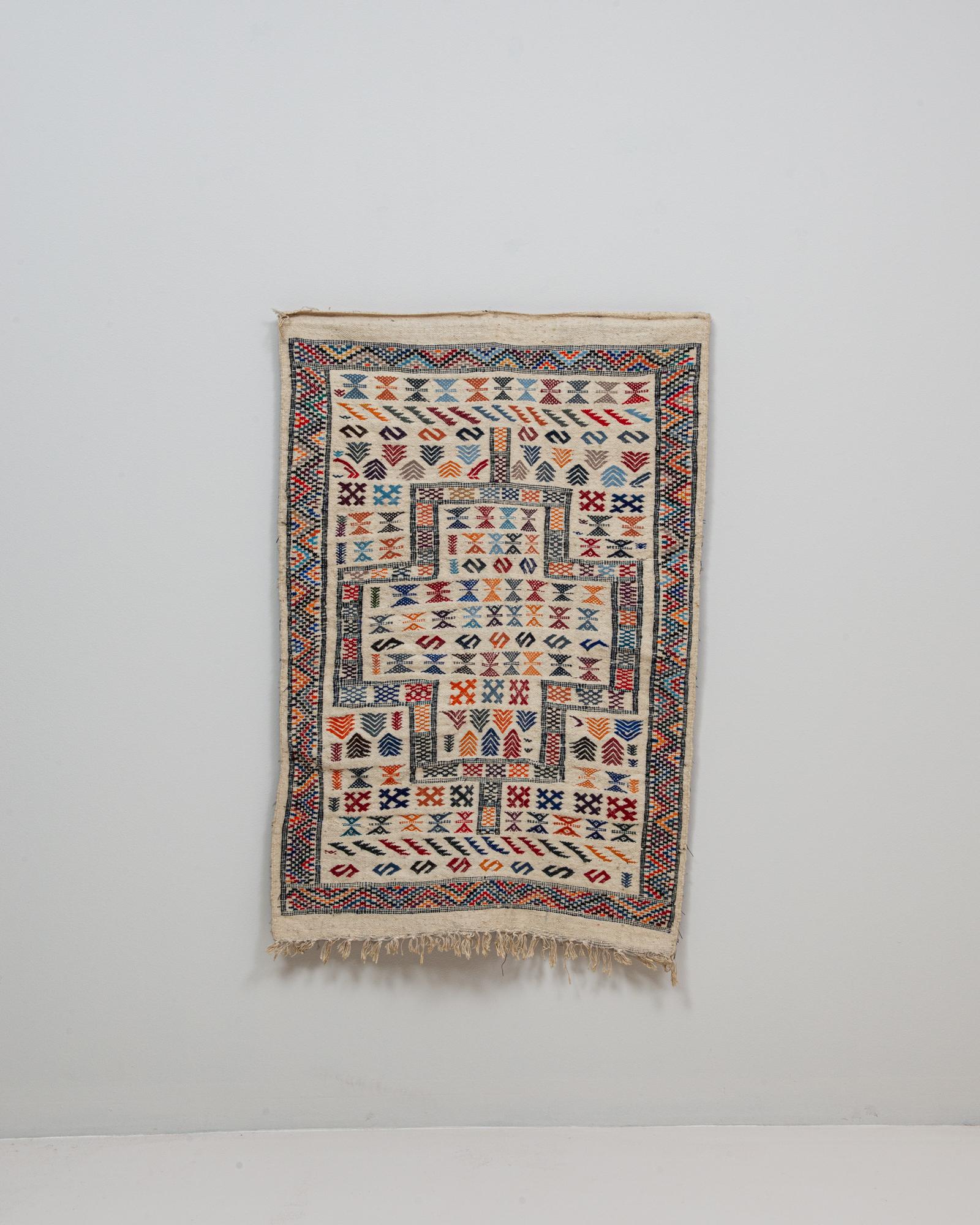 Ce tapis oriental danois du XXe siècle présente un motif géométrique vibrant inspiré du tissage tribal traditionnel, interprété avec une sensibilité scandinave. Sur un fond ivoire chaud, le tapis présente des formes de médaillons en escalier et des