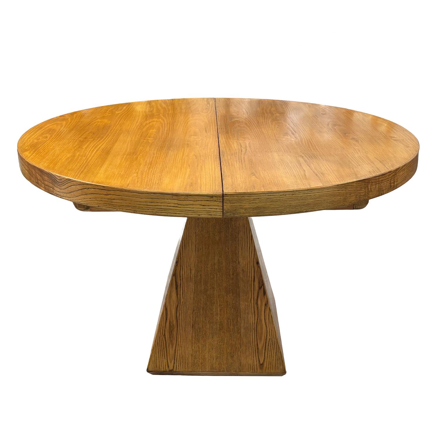 A vintage Mid-Century Modern oval extendable dining table, crafted in pinewood with a mission edge. The table top is sitting on a single trapezoid base, giving it a distinctive architectural balance and sculptural presence. The extendable design