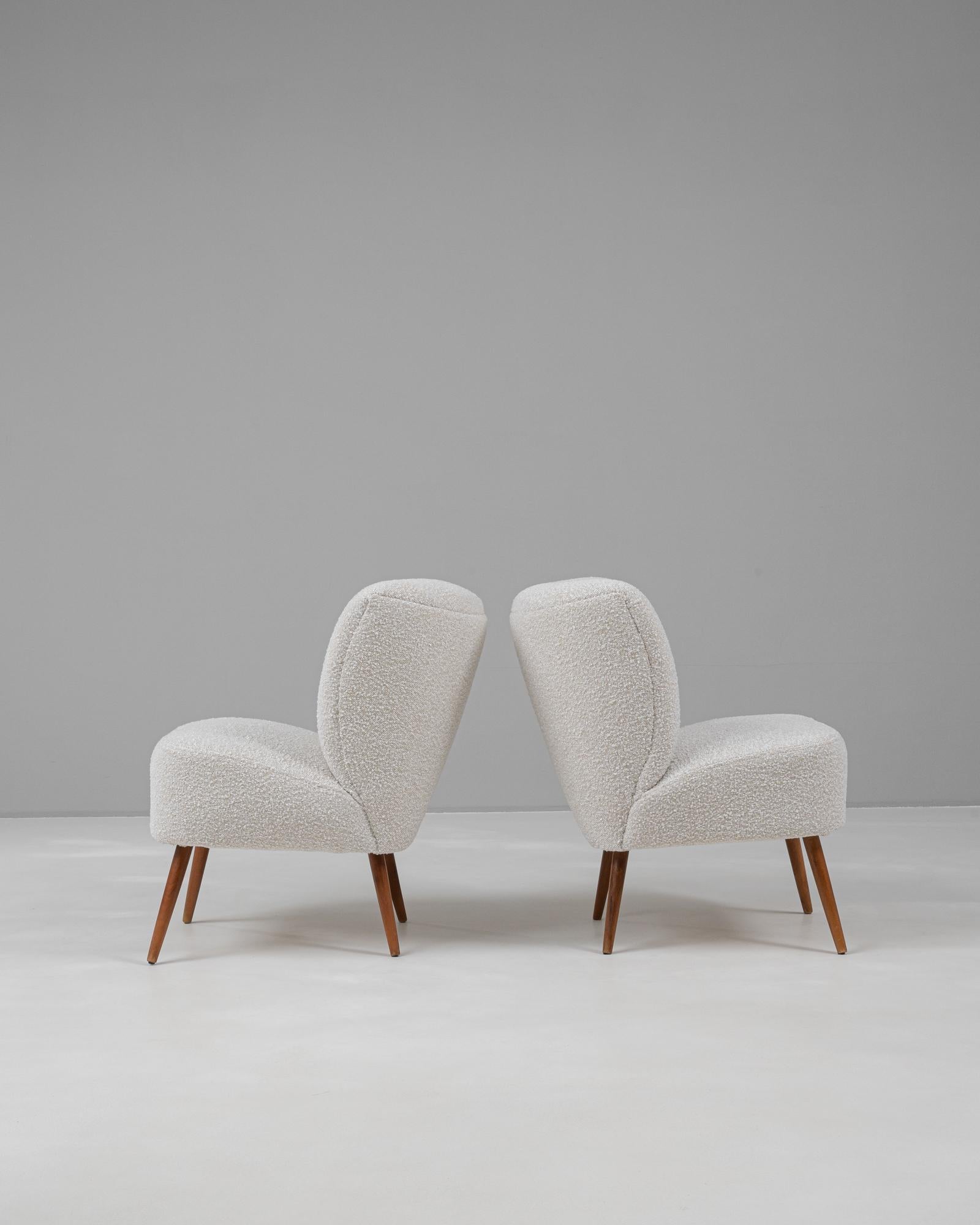 This delightful pair of 20th-century Danish upholstered chairs exudes mid-century modern charm and Scandinavian minimalism. The chairs are characterized by their softly curved backs and plush seats, upholstered in a textured neutral fabric that