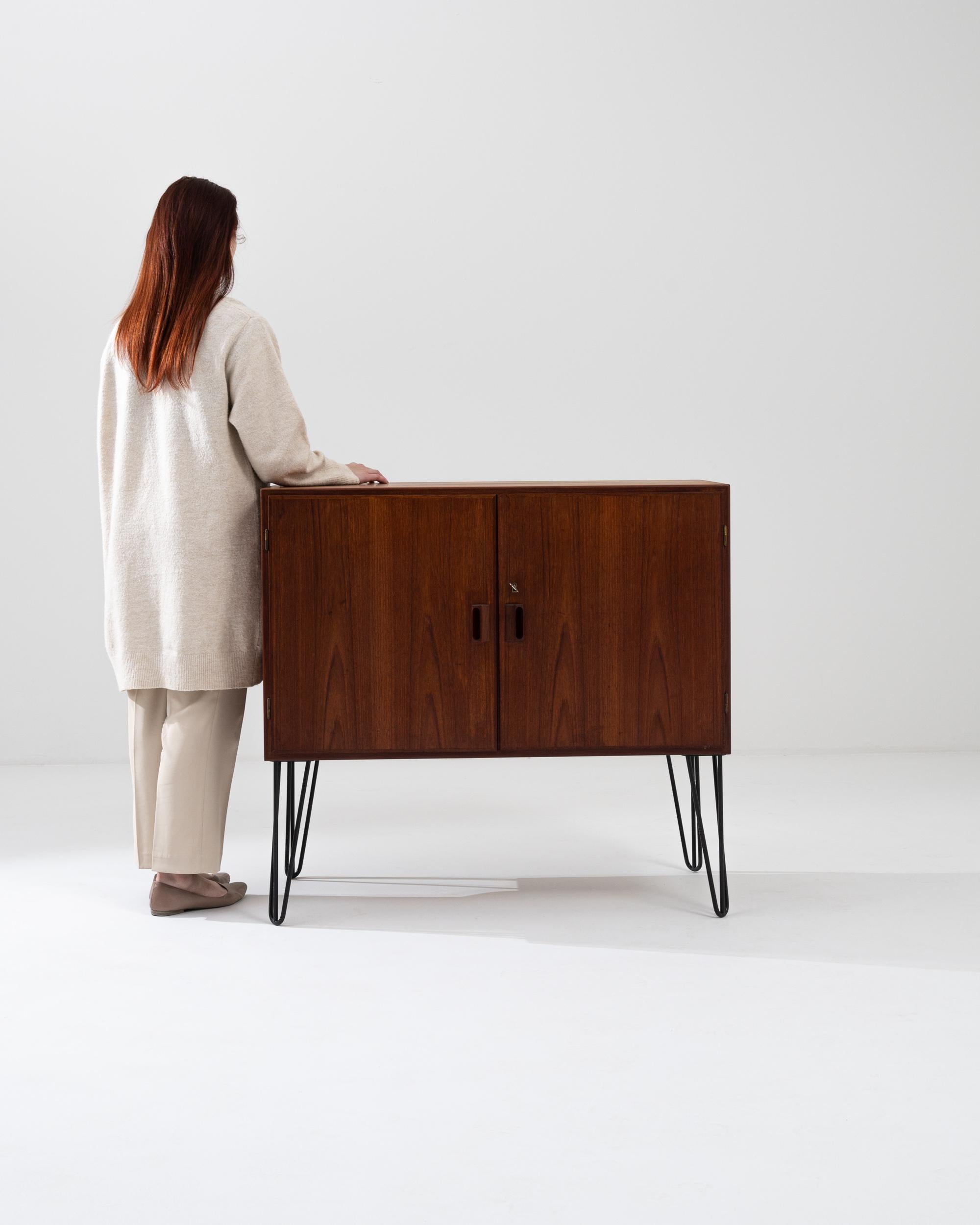 Combining a geometric silhouette with the opulent warmth of teak, this vintage console cabinet offers a delightful Mid-Century Modern collector’s piece. Made in Denmark in the 20th century, the clean lines of the rectilinear case speak to a
