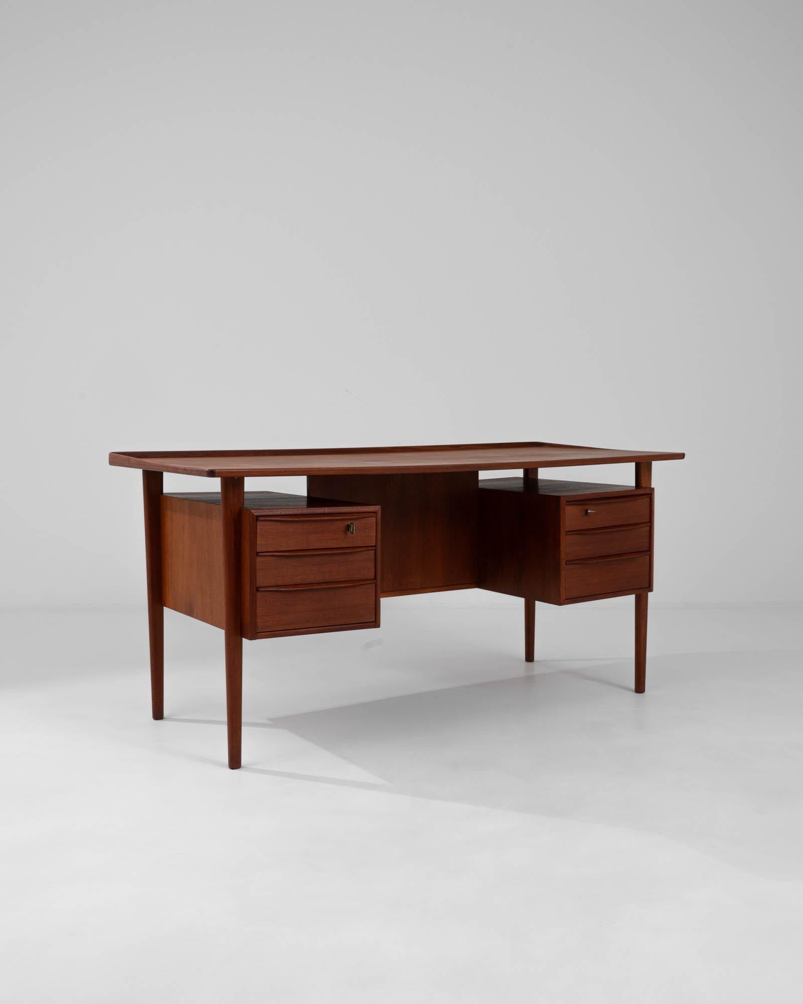 Infuse your workspace with the timeless elegance of Scandinavian design with this 20th Century Danish Teak Desk by Peter Løvig Nielsen. Crafted from rich teak wood, known for its durability and warm hue, this desk epitomizes mid-century modern style