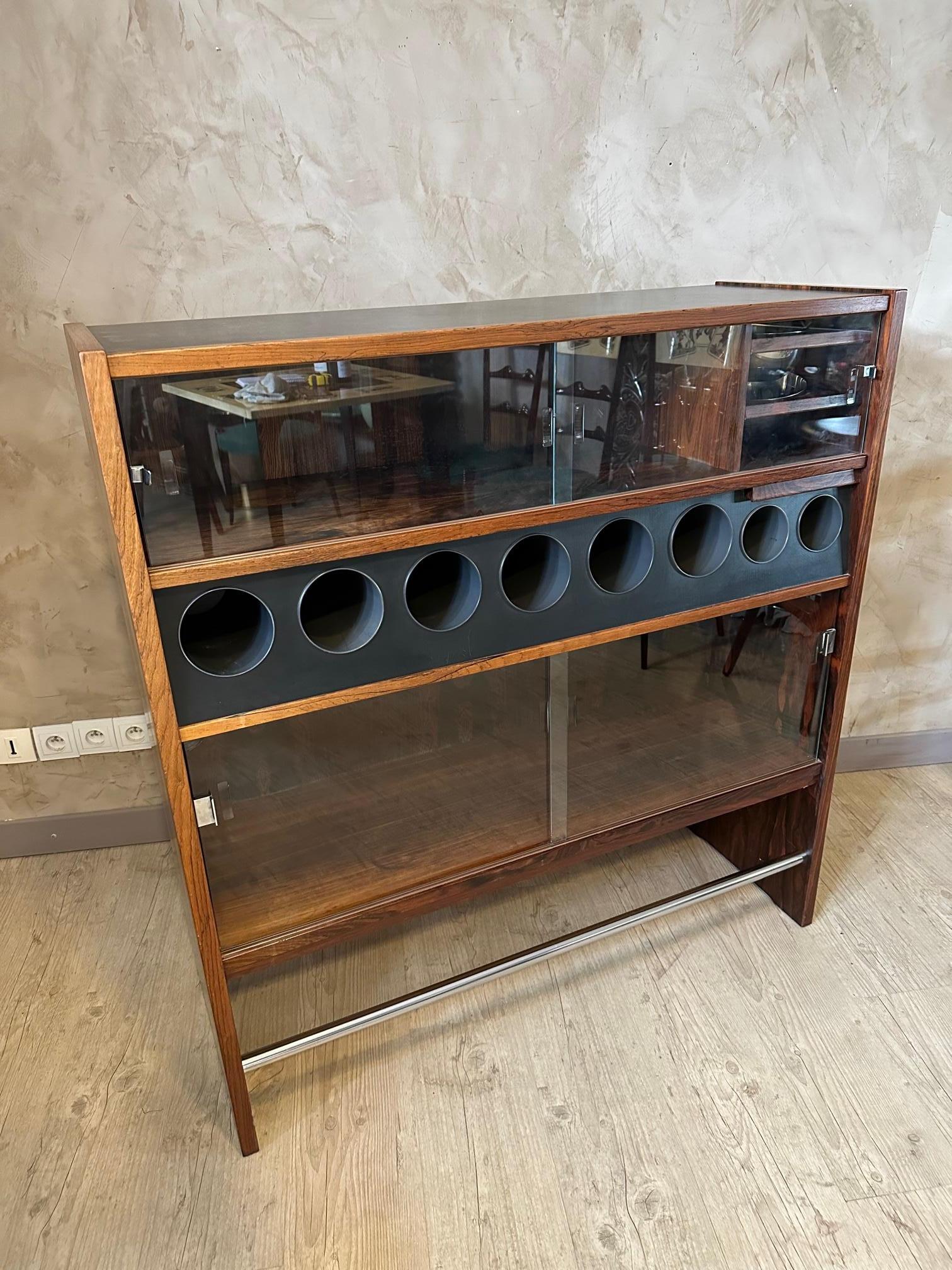 Very nice teak bar and its three Danish stools designed by Erik Buch for Oddense Maskinsdkeri in the 60s. Very good condition.
Bartender side: 8 bottle compartments, two bowls for ice cubes and utensils, a shelf for glasses. Several shelves closed