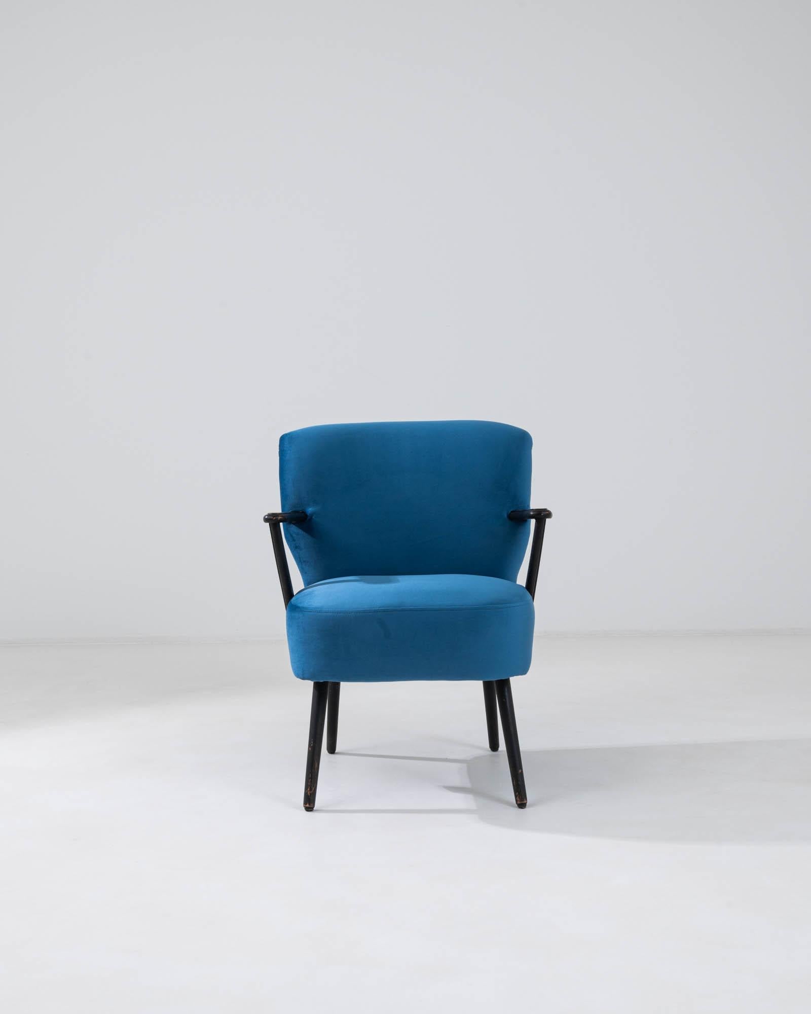 Enliven your space with the vibrant allure of this 20th Century Danish upholstered armchair, a piece that artfully combines mid-century design with contemporary comfort. Cloaked in a striking shade of blue, the chair's fabric is both an aesthetic