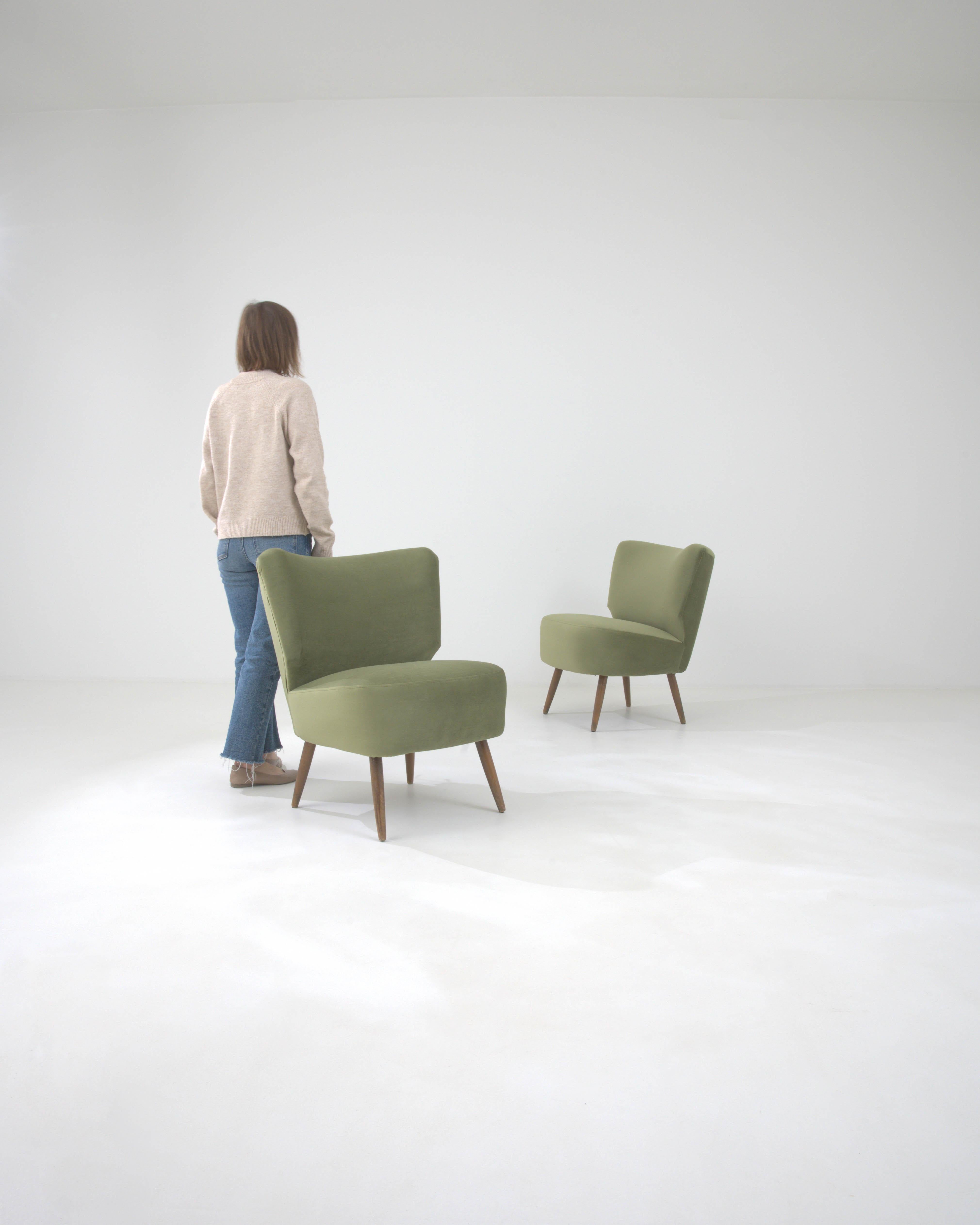 Embrassez l'élégance intemporelle du design du milieu du siècle avec notre paire de fauteuils tapissés danois du 20e siècle. Chaque chaise témoigne du savoir-faire de l'époque, avec un tissu vert moelleux qui invite à s'asseoir et à se détendre. Les
