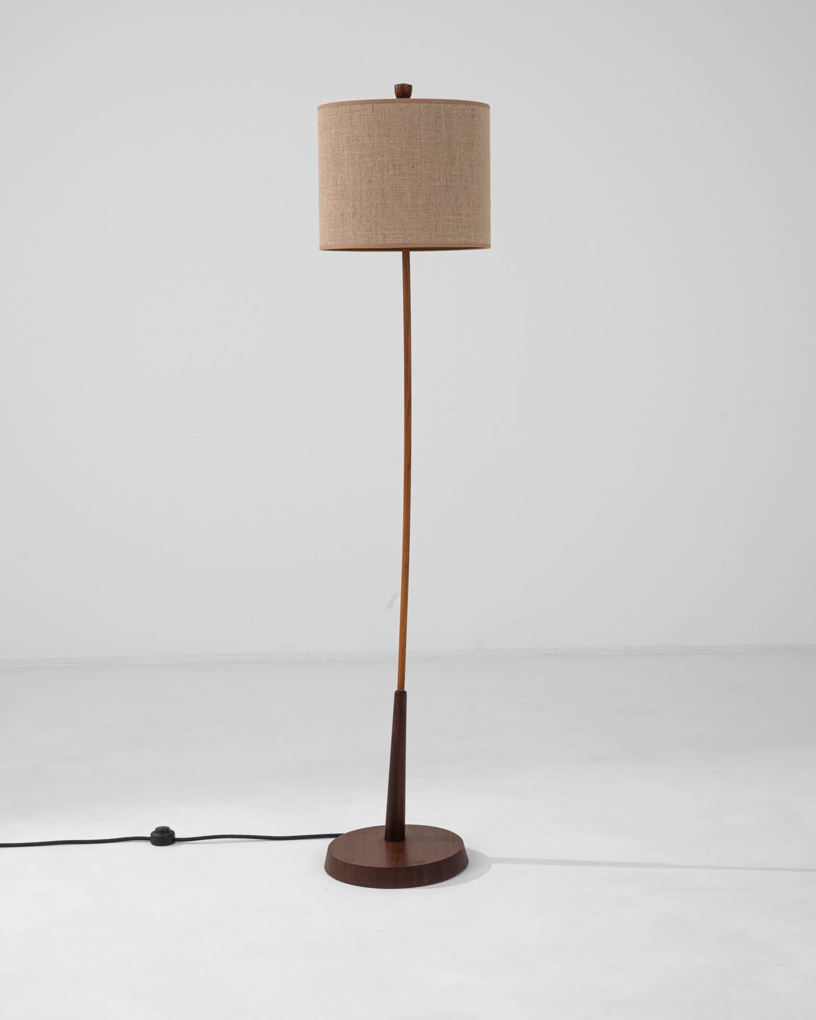 Illuminate your living space with the understated elegance of this 20th Century Danish Wooden Floor Lamp. Meticulously crafted, this lamp stands tall on a foundation of rich, dark-stained wood that highlights the natural beauty of its grain. The