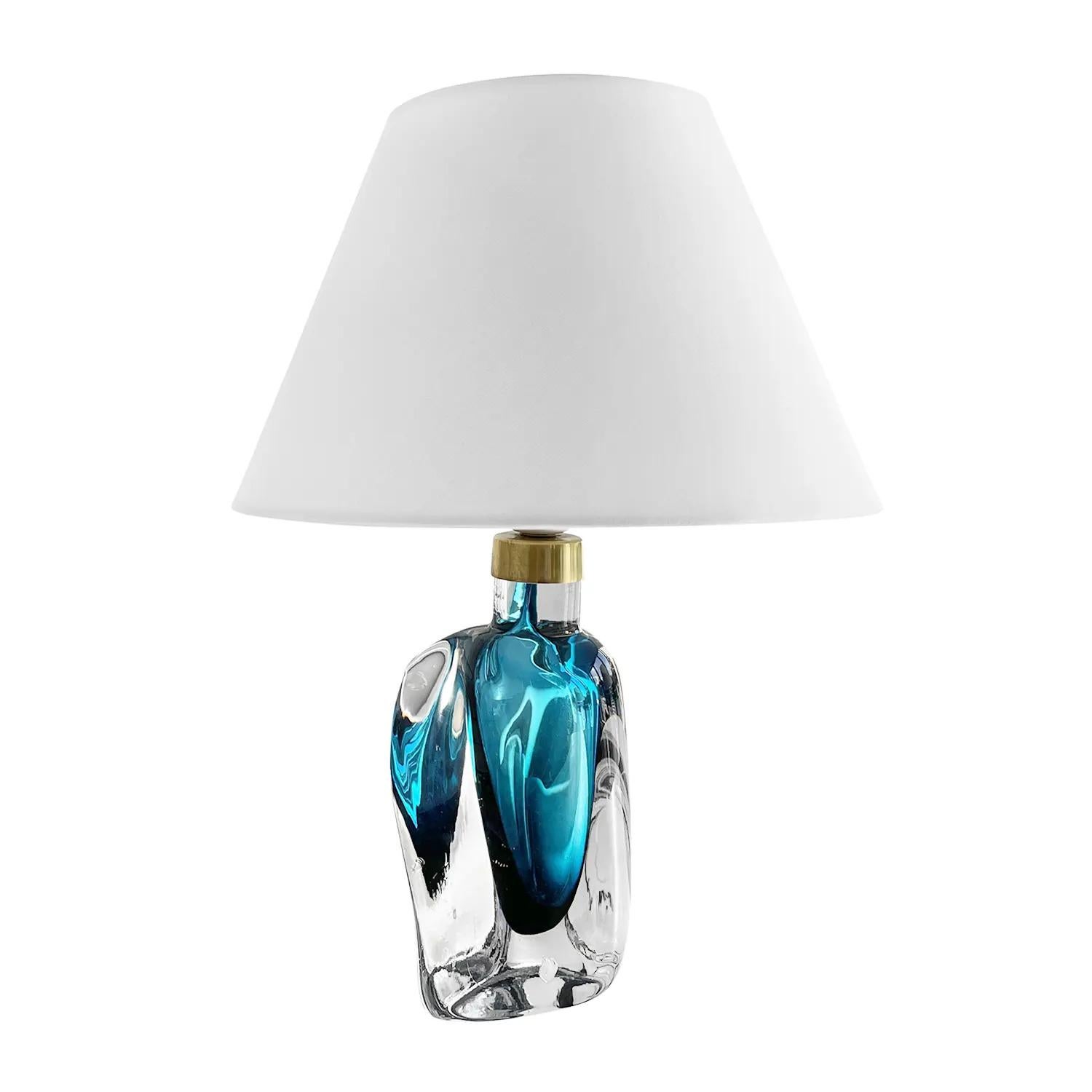 A dark-blue, vintage Mid-Century modern Swedish table lamp made of hand blown smoked Murano glass, the beam is enhanced with a polished brass ring, in good condition. The sculptural Scandinavian desk light was produced by Orrefors, composed with a