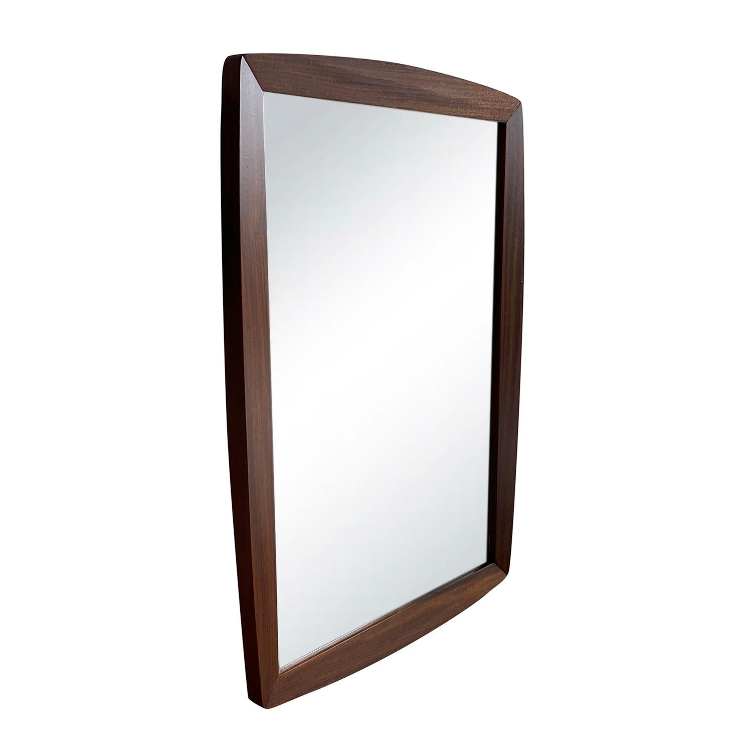 A small dark-brown, vintage Art Deco Danish wall mirror made of hand carved Walnut, in good condition. The mirrored glass is original. Wear consistent with age and use, circa 1930 - 1950, Denmark, Scandinavia.