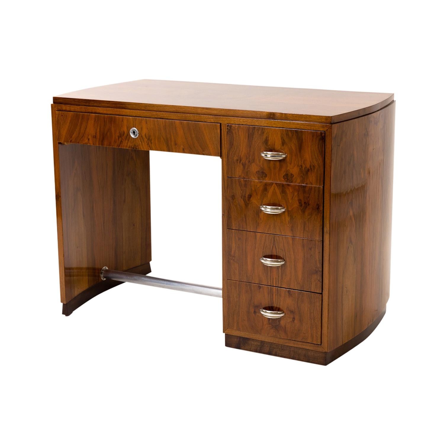 A vintage French Art Deco writing table with rounded sides, made of hand crafted polished, partly veneered Walnut with a tubular steel footrest, in good condition. The freestanding desk is composed with four small drawers and chrome handles, pulls,