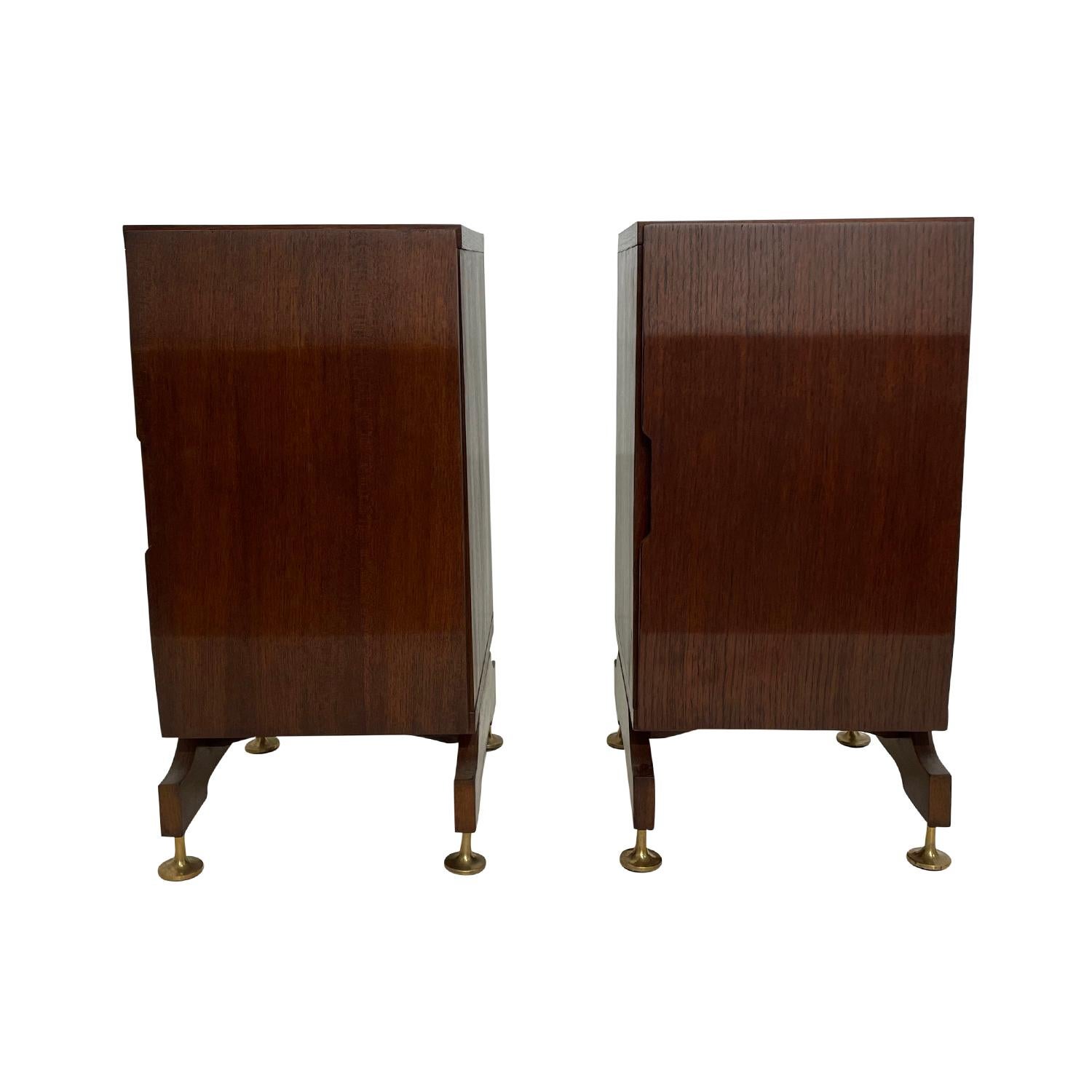 A dark-brown, vintage Mid-Century Modern Italian pair of nightstands made of hand crafted polished Walnut, in good condition. Each of the rectangular bed side tables are composed with a door and interior shelving, resting on an arched wooden base,