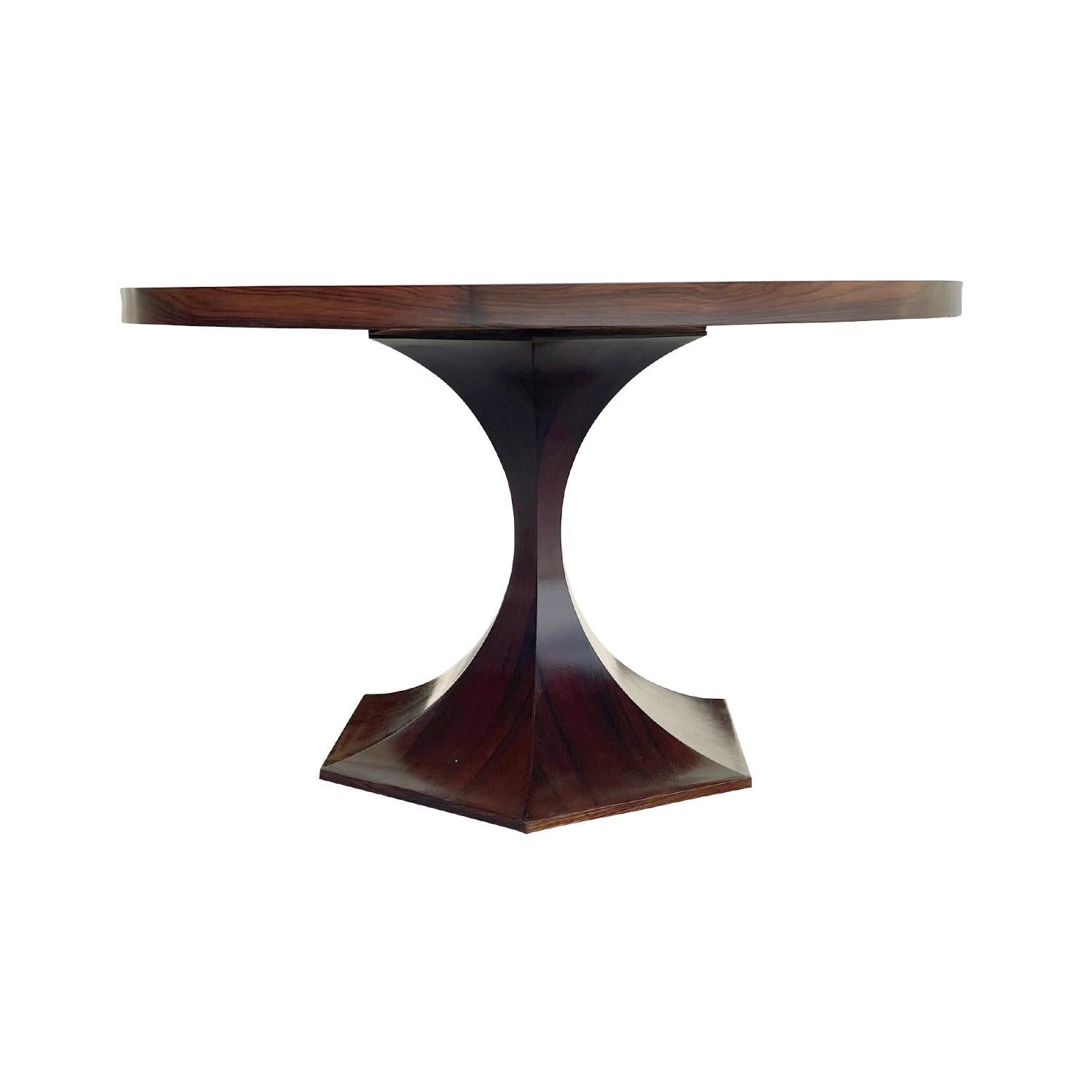 A round, vintage Mid-Century modern Italian dining room table made of hand crafted polished Rosewood, in good condition. The small center table is composed with a round table top, supported by a sculptural wooden base, enhanced by detailed wood