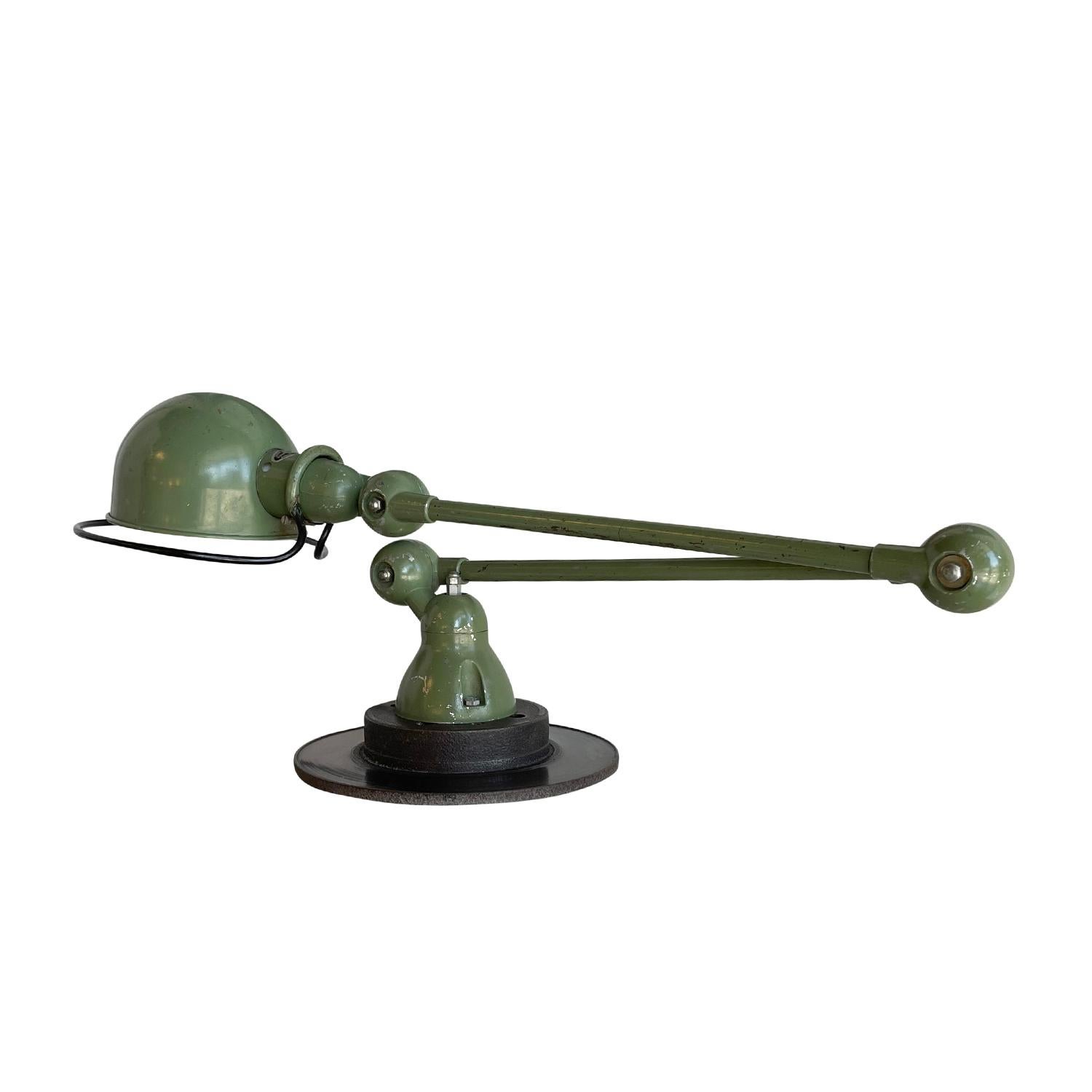 A dark-green, vintage Mid-Century Modern French desk light made of handcrafted metal, designed by Jean Louis Domecq and produced by Jielde, in good condition. The industrial car brake, table lamp is composed with two adjustable arms, featuring a one