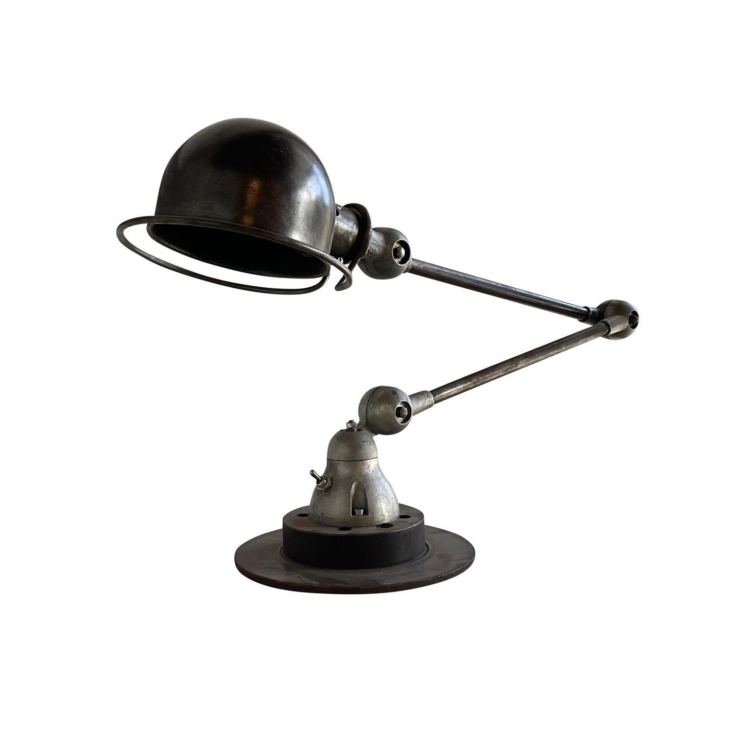 A dark-grey, vintage Mid-Century Modern French desk light made of hand crafted metal, designed by Jean Louis Domecq and produced by Jielde, in good condition. The industrial car brake, table lamp is composed with two adjustable arms, featuring a one