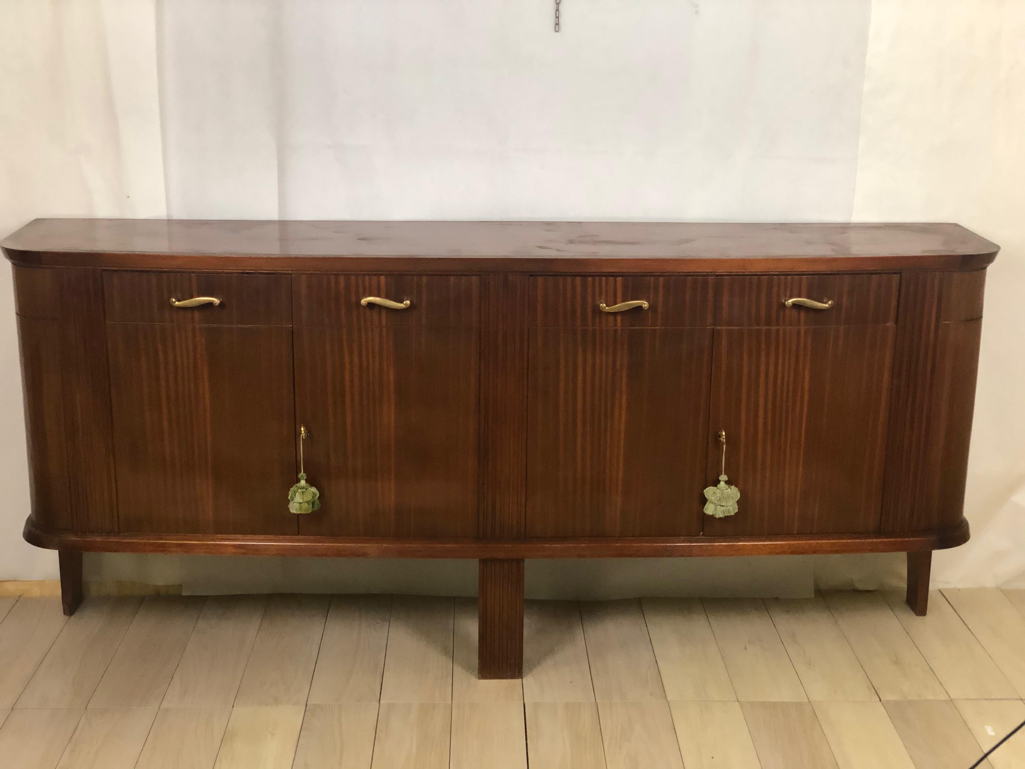Interesting sideboard in light mahogany with 4 drawers and 4 doors resting only on three feet of the slim profile with light grooves.
Very intriguing design, suitable as a sideboard, but also very comfortable for a bathroom cabinet. In perfect