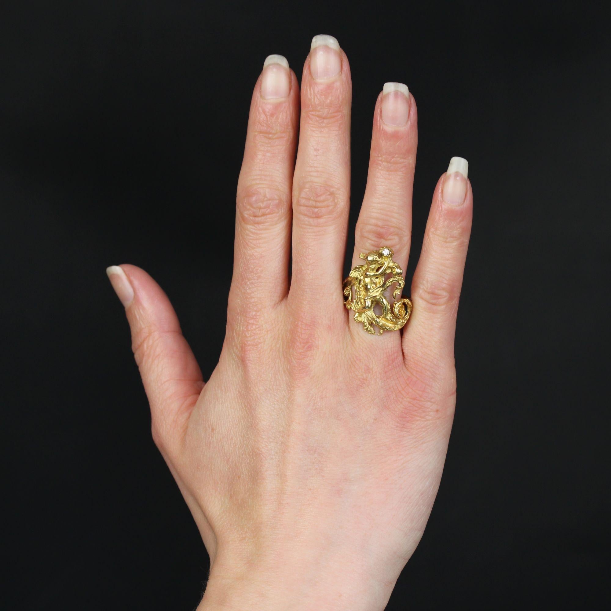 Ring in 18 karat yellow gold.
An important antique ring, its setting is engraved all around and on top with plant motifs, arabesques and an adorable little angel holding a small brilliant-cut diamond in her hands above her head. The whole is