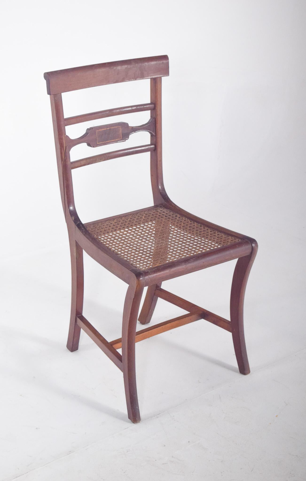Chaise de salle à manger avec dossier en paille. De style Empire, avec un dossier composé de trois traverses horizontales, celle du centre étant ornée d'une découpe géométrique et d'une incrustation contrastée. La structure présente des lignes
