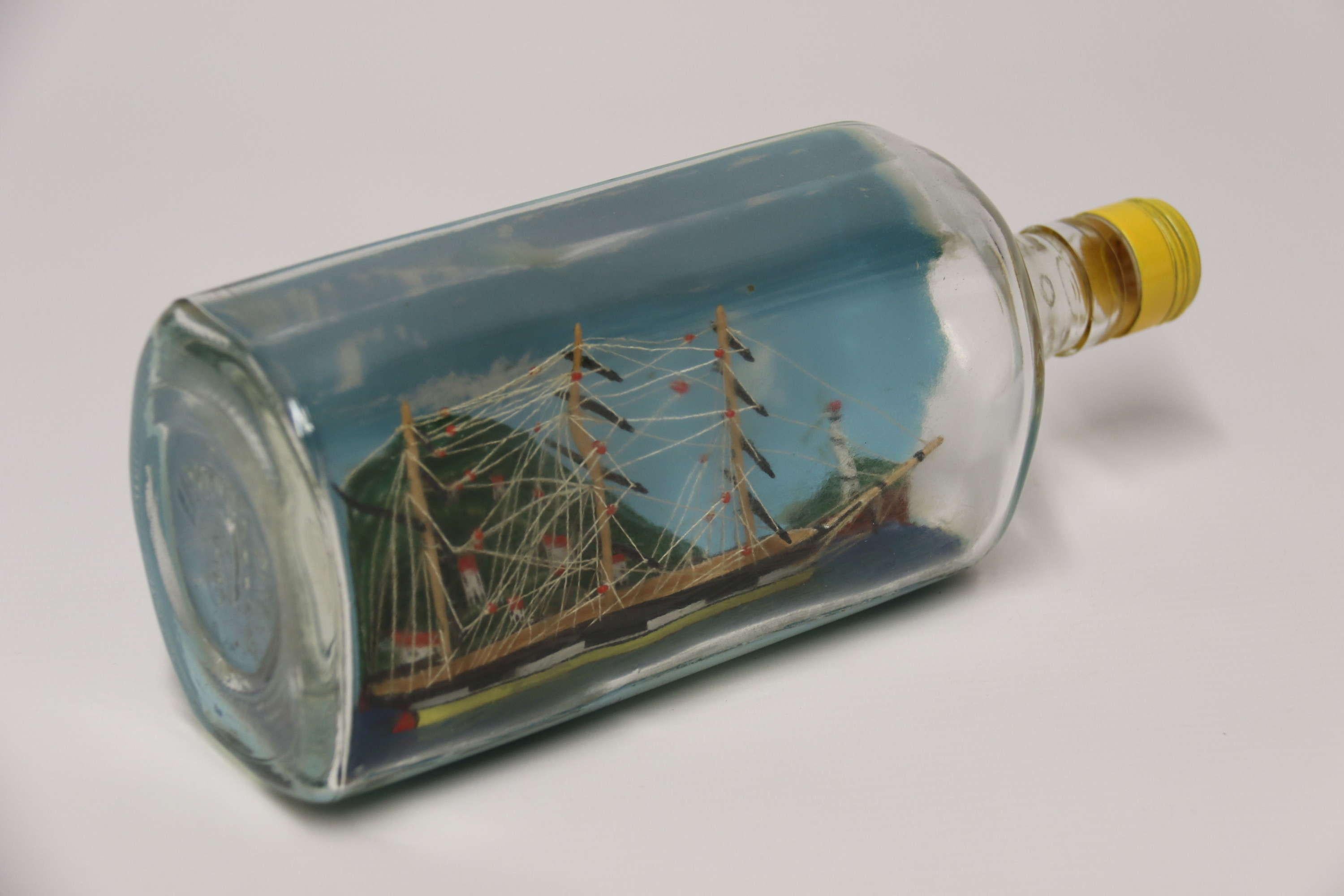 Ein feines Diorama Volkskunst Modell Schiff in einer Flasche

Dieses kunstvoll gefertigte Diorama zeigt ein dreimastiges Segelschiff aus dem frühen 19. Jahrhundert im Hafen, dahinter eine erhöhte Landschaft mit in den Hang eingelassenen Häusern