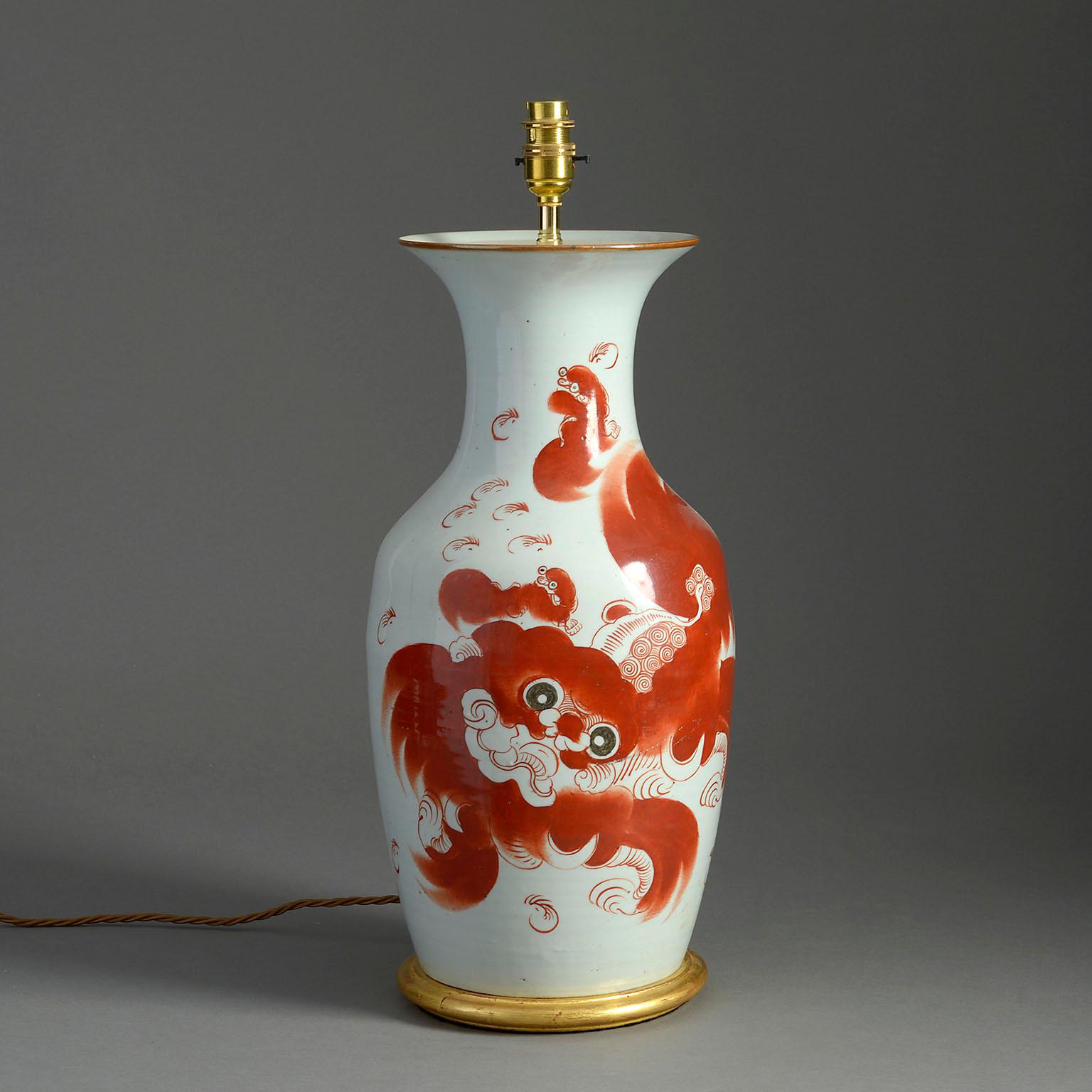 A twentieth century porcelain baluster vase of good scale, decorated with a red dog of fo upon a white ground, the reverse side with Chinese characters. Mounted on a turned giltwood base as a table lamp.

Dimensions refer to vase and giltwood base