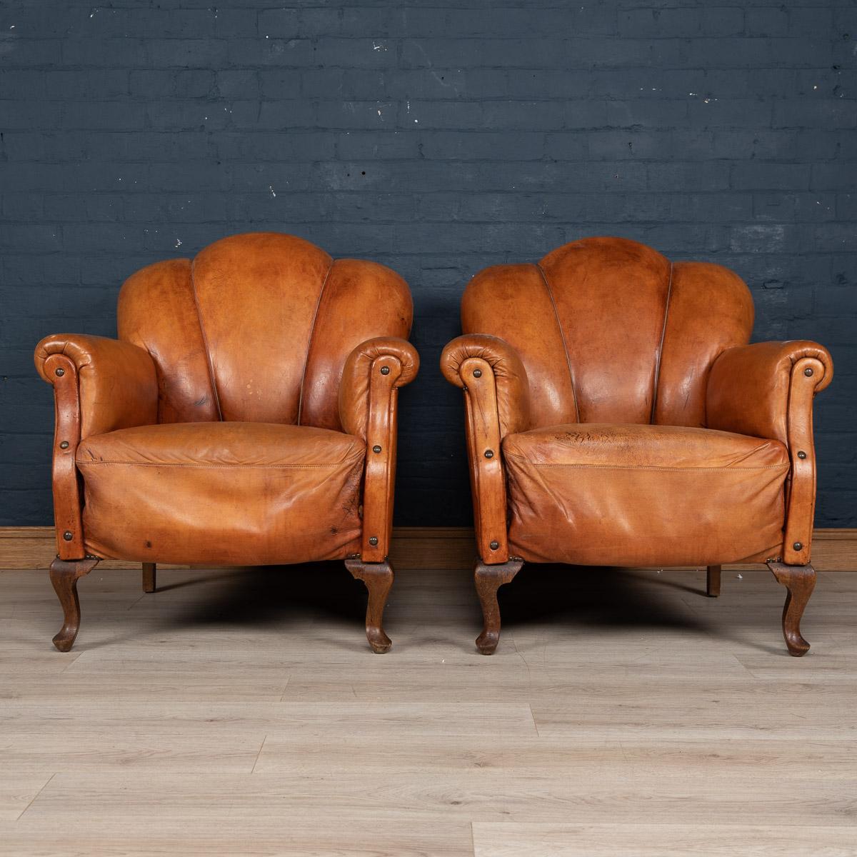 A wonderful pair of leather scallop-back armchairs. Dating to the middle to late part of the 20th century these chairs were realised by the finest Dutch craftsmen, the solid wood frame upholstered in superb quality leather which over the years have