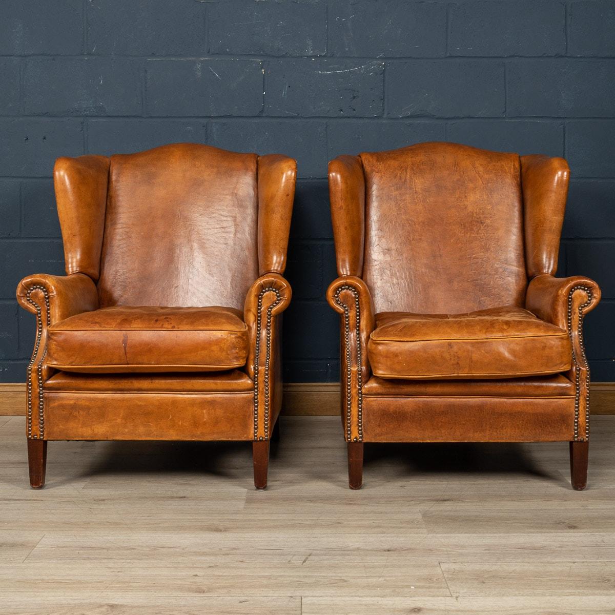 Ein wunderbares Paar lederne Ohrensessel. Die Stühle stammen aus der zweiten Hälfte des 20. Jahrhunderts und wurden von den besten niederländischen Handwerkern gefertigt, wobei der Massivholzrahmen mit hochwertigem, honigfarbenem Schafsleder