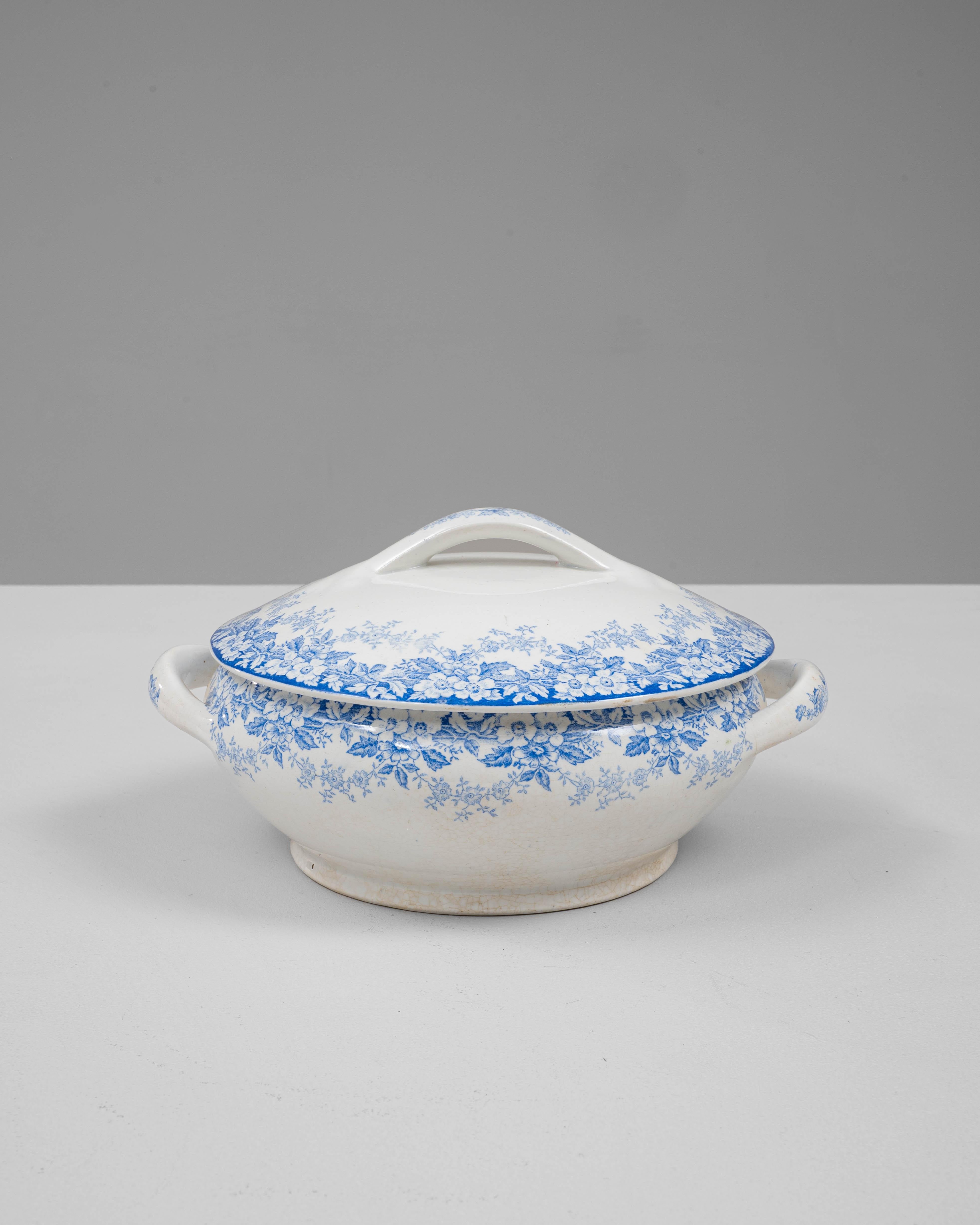 Cette soupière en porcelaine hollandaise du 20e siècle, édition spéciale avec couvercle, présente une élégante silhouette arrondie ornée d'un délicat motif floral bleu transféré qui s'enroule gracieusement autour du corps et du couvercle en forme de