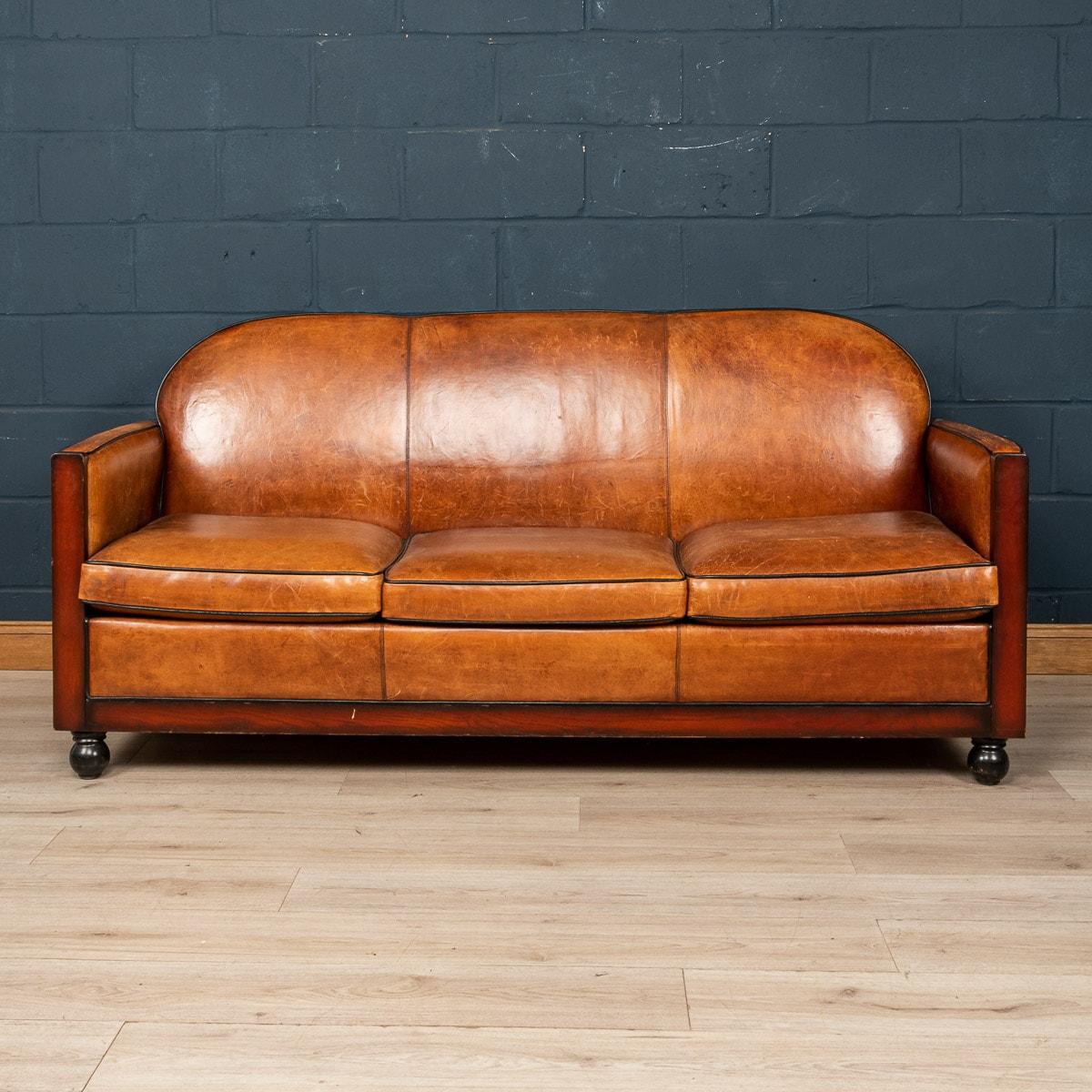 Showing superb patina and colour, this wonderful sofa was hand upholstered in sheepskin leather in Holland by the finest craftsmen in the latter part of the 20th century. This particular model showing strong Art Deco influence thanks to its straight