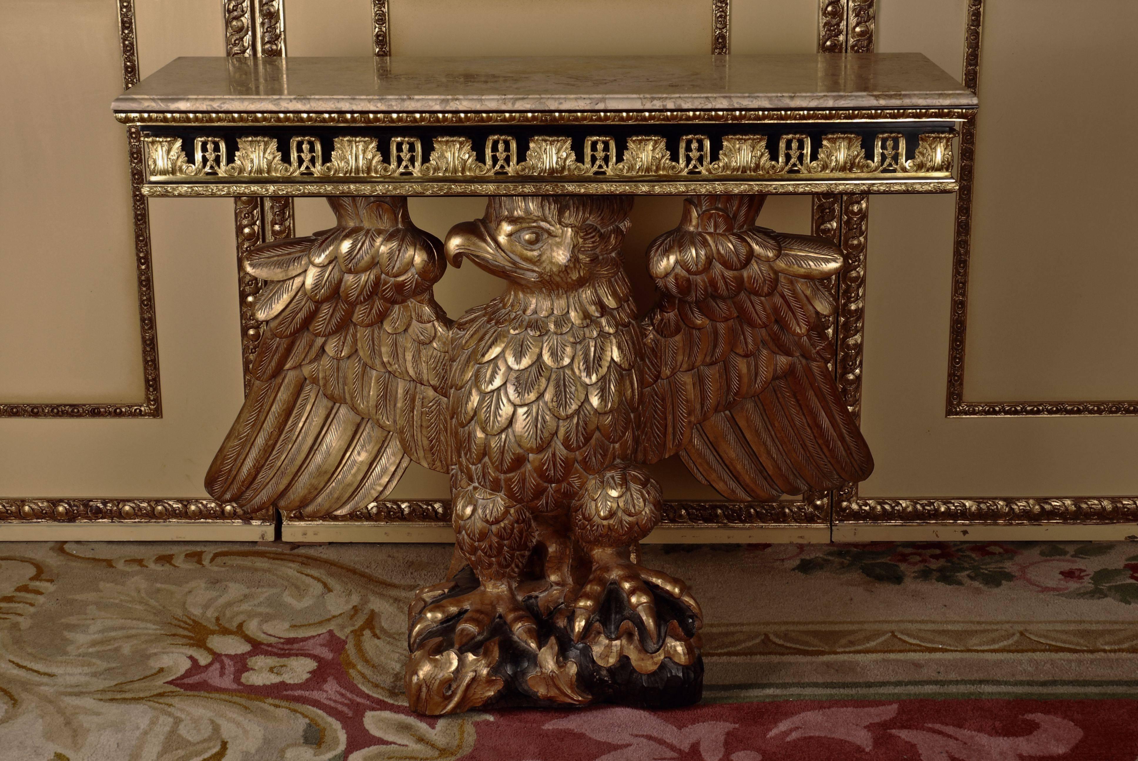Imposing eagle console after a model by William Kent, 1685-1748.
A console from the Regency period, approximately. Monumental fully moulded hand-carved eagles from solid Beech. Partial black hand-painted and gilded. Standing on a slab. Frieze of