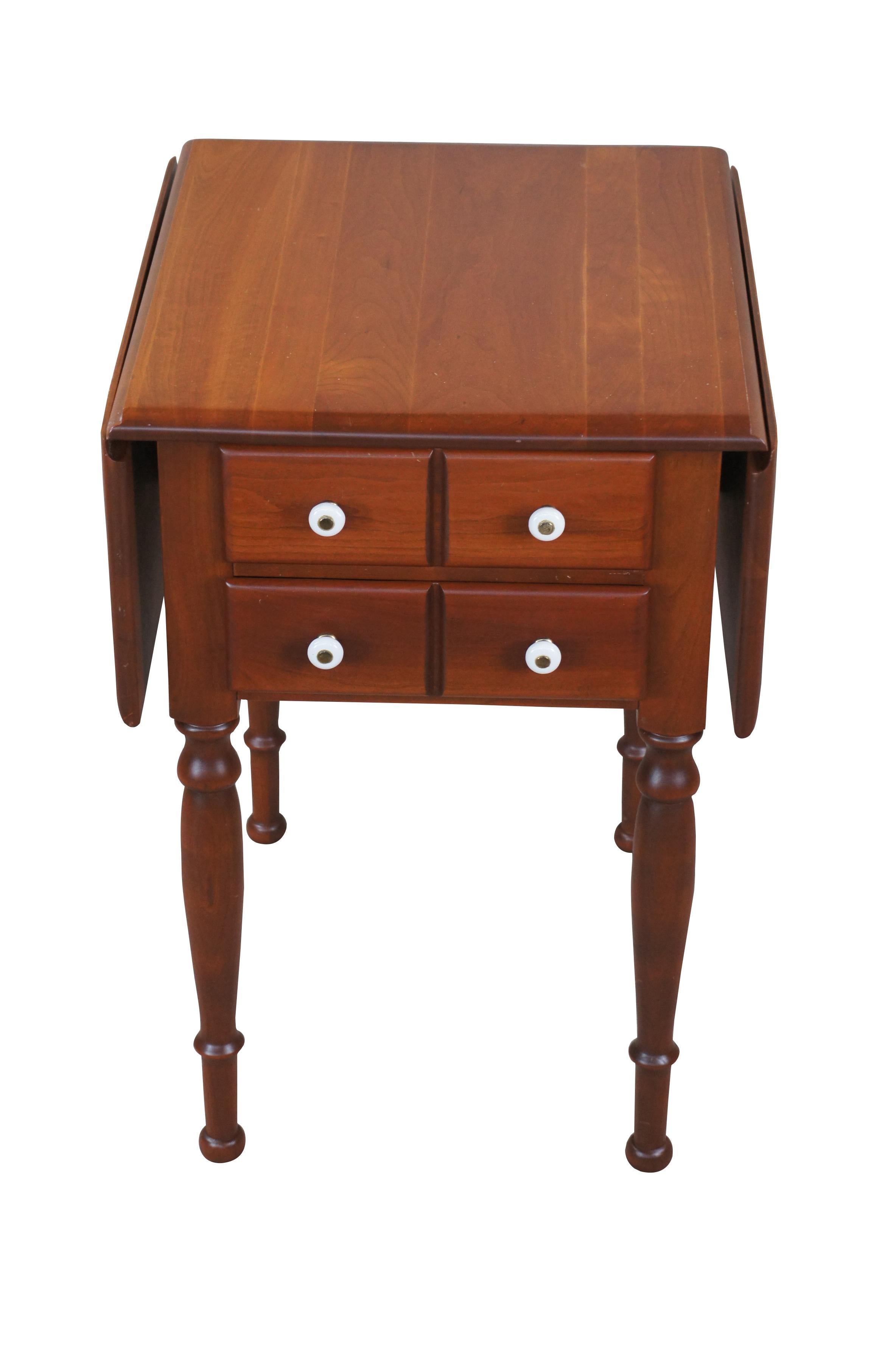20th Century Early American style drop leaf accent table.  Made of cherry featuring rectangular form with two drop leaves, two drawers with porcelain pulls, and turned legs.

Dimensions: 
18