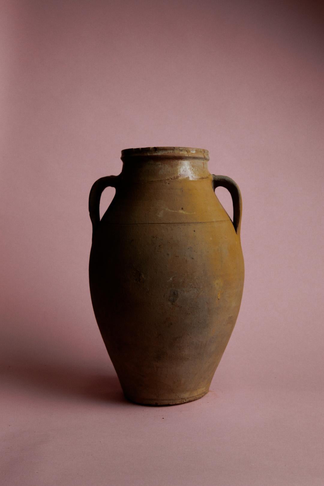 Apportez de la chaleur et de l'histoire dans votre maison avec cette jarre de stockage en argile turque aux tons miel, un chef-d'œuvre du XXe siècle provenant d'Anatolie, réputée pour ses riches traditions en matière de poterie. Cette jarre, qui