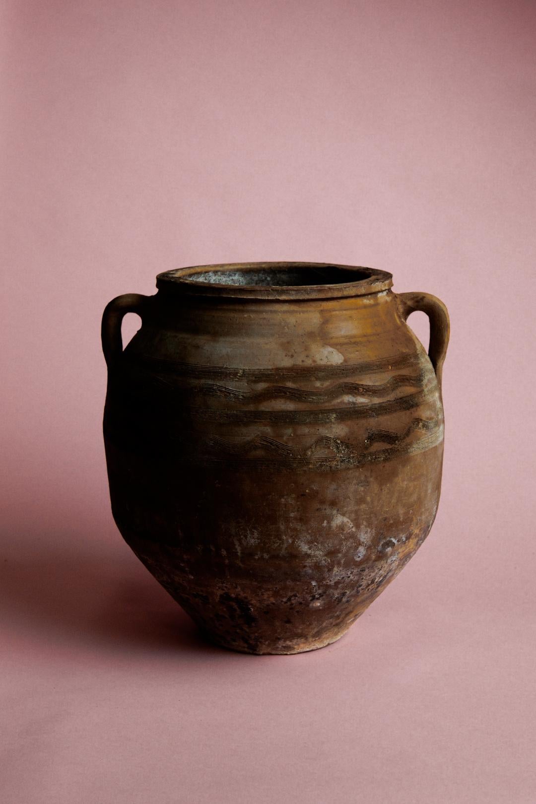 Porta la storia e il calore nel tuo spazio con questo vaso turco con manico marrone, un manufatto del XX secolo proveniente dall'Anatolia, famosa per le sue ricche tradizioni ceramiche. Originariamente utilizzato per conservare cereali o liquidi,